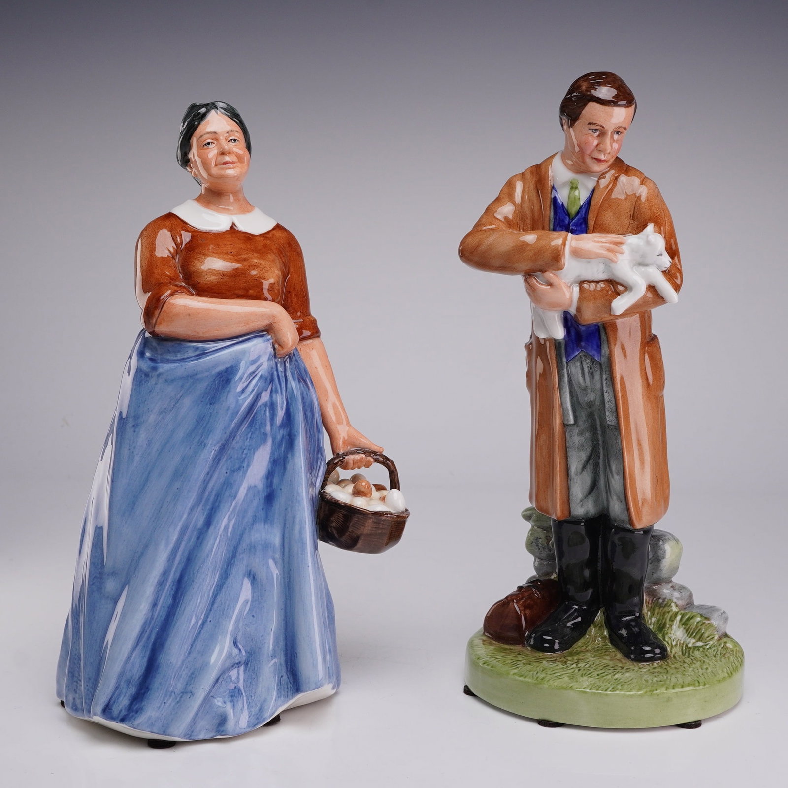 Two Royal Doulton Figurines, Farmer's Wife HN3164 and Country Veterinary HN4650: The first figurine is titled Farmer's Wife, model number HN 3164, and was modeled by Adrian Hughes. The figure depicts a woman in traditional rural attire, including a brown blouse with a white collar