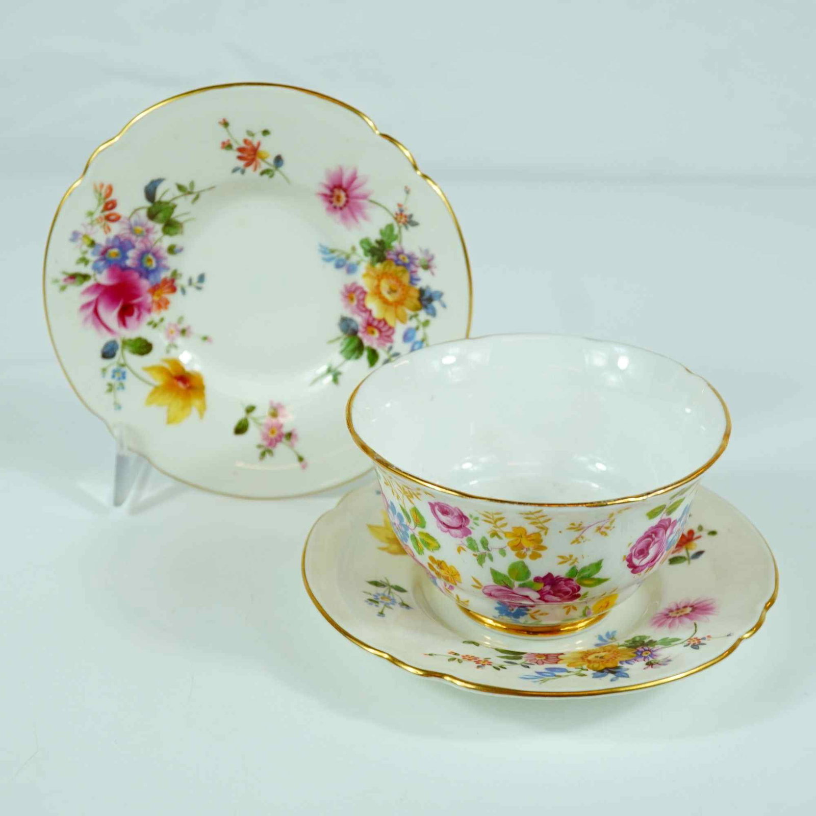 3pc Royal Stafford June Roses Bowl and Royal Crown Derby Derby Posies Saucers: Royal Stafford June Roses and Royal Crown Derby Derby Posies are the patterns identified for this three-piece ceramic lot. The set consists of one handleless tea bowl and two saucers. The tea bowl, in
