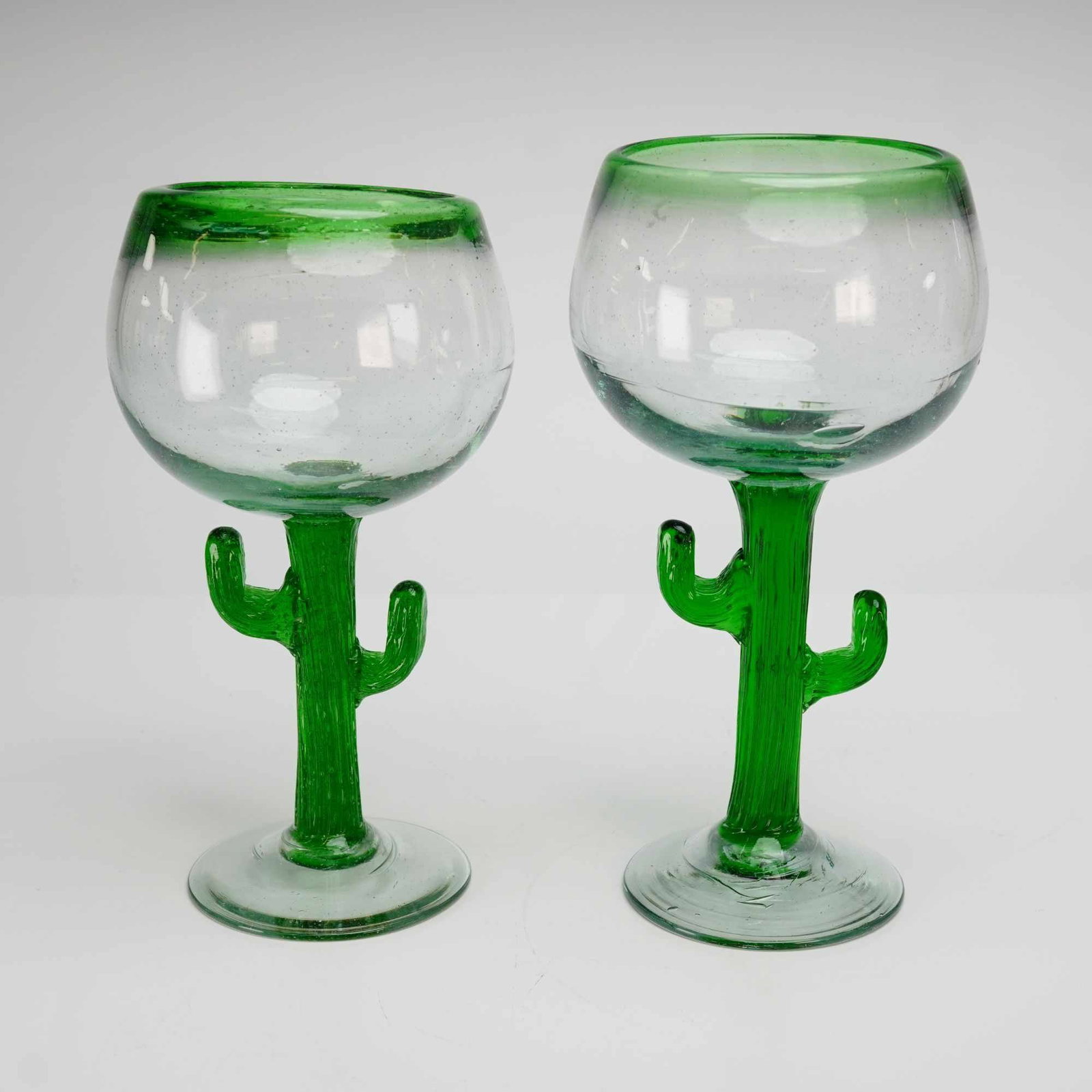 Artisan Mexican, Hand-Blown Bubble Glass Cactus Stem Margarita Goblets, Pair: This pair of hand-blown glass goblets features a whimsical saguaro cactus design, characteristic of artisan-made glassware produced in Mexico. The pieces are crafted from bubble glass, a style defined