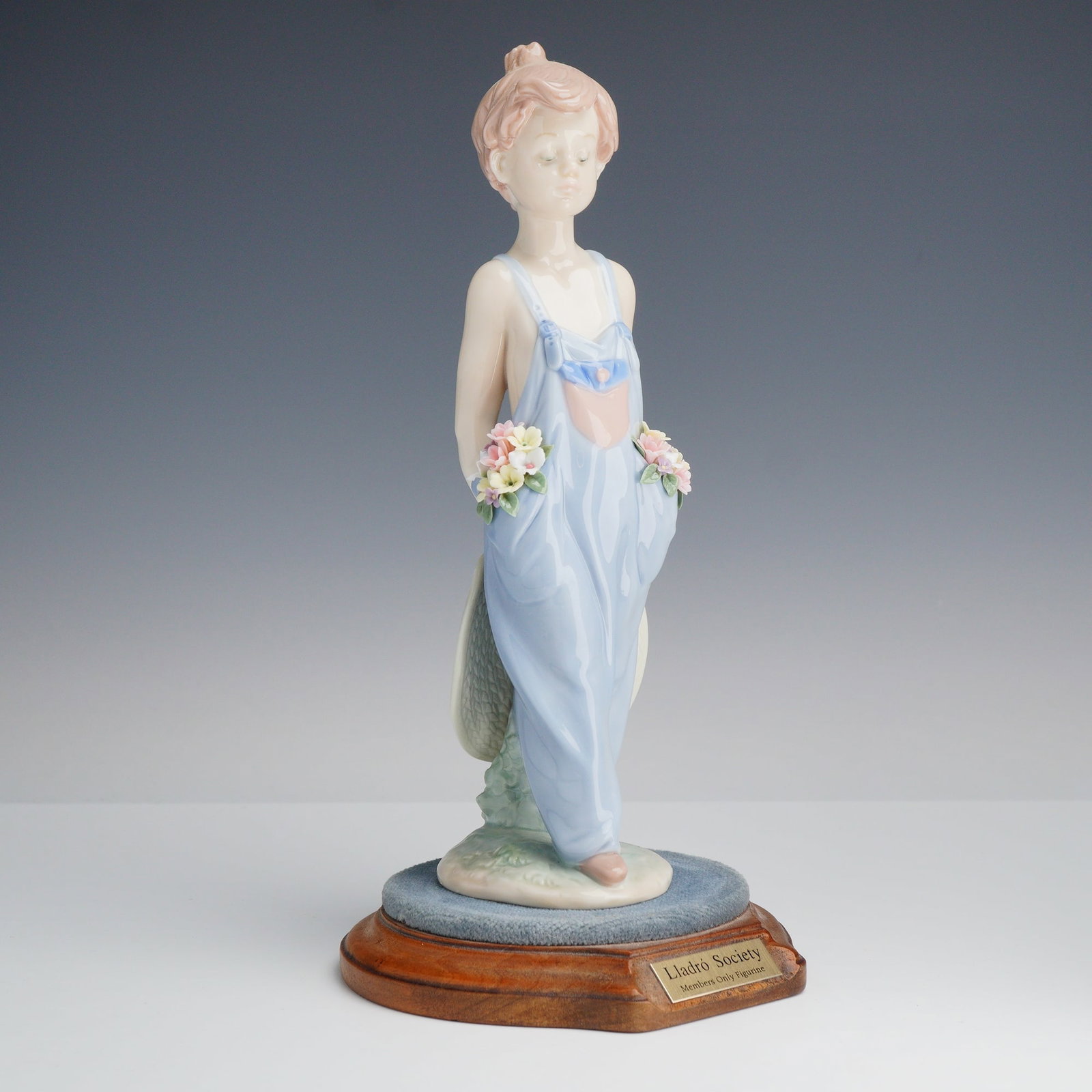 Lladro Collectors Society Porcelain Figurine Pocket Full of Wishes 01007650 with Base: This Lladro porcelain figurine, model number 7650, is titled Pocket Full of Wishes. The piece depicts a young boy standing in a relaxed pose wearing light blue denim-style overalls. Small,