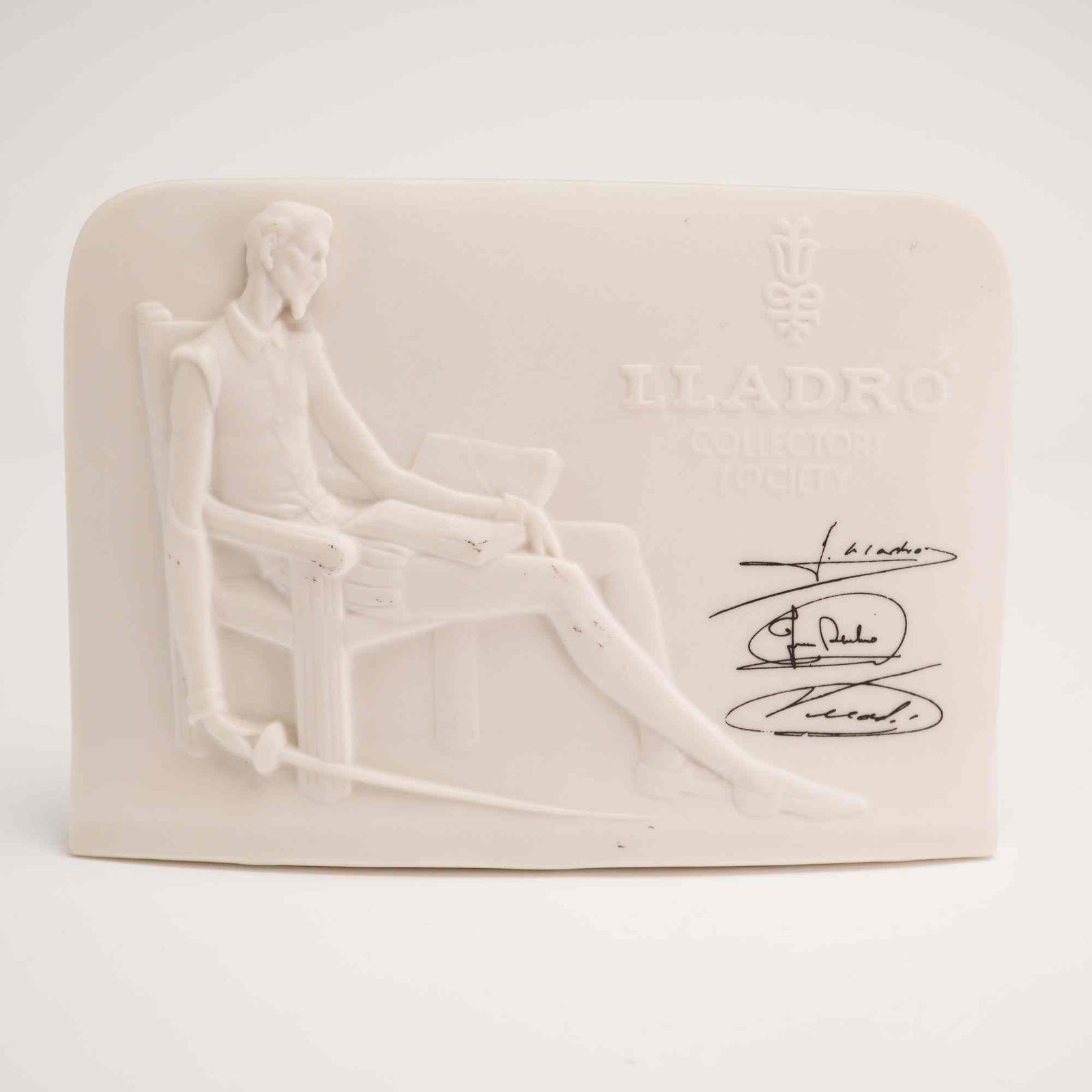 Lladro Matte Porcelain Charter Member Plaque, Don Quixote 01017601: Signed Collectors Society tablet displaying Don Quixote with a book and a sword, issued 1985. Lladro backstamp. Dimensions: 6.00"L x 2.25"W x 4.25"H Weight: 11.00oz