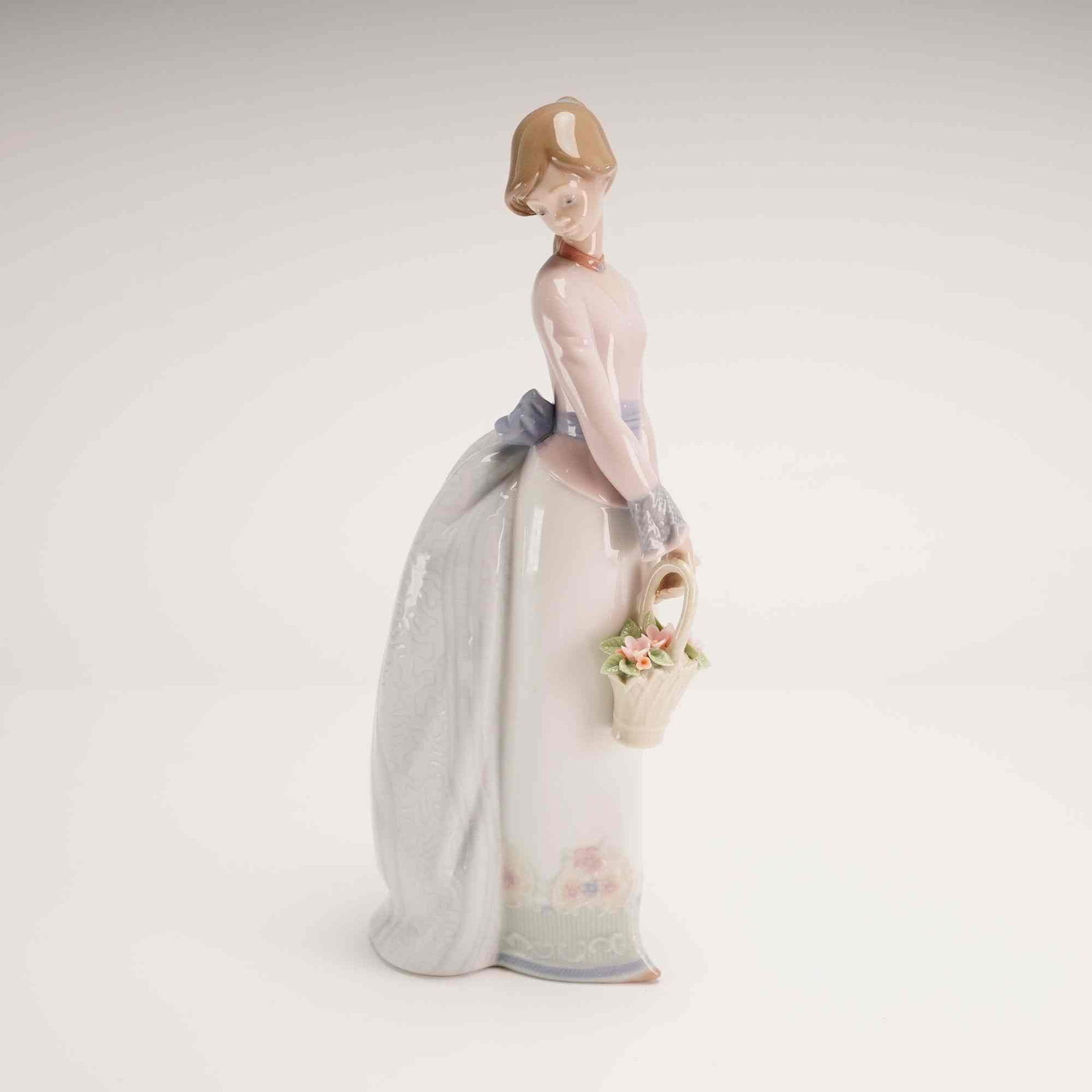 Lladro Porcelain Figurine Basket of Love 01007622 with Box: A glazed porcelain figurine titled Basket of Love, model number 01007622 (7622), designed by sculptor Jose Puche for Lladro. This piece was issued as the 1994 Collectors Society annual figurine. The w