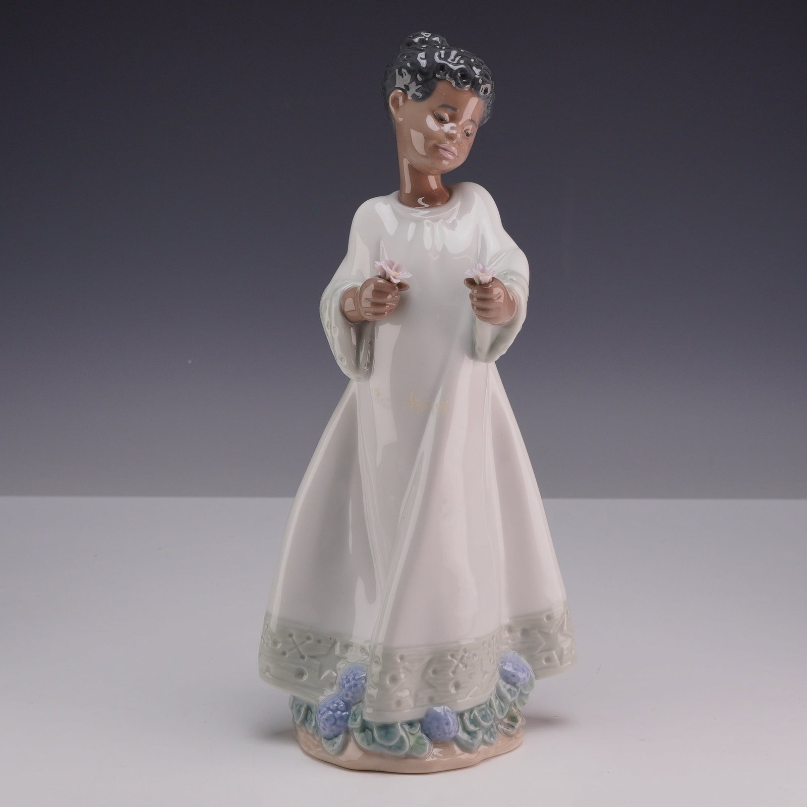 Lladro Porcelain Figurine Enchanting 01006808 with Original Box: This Lladro porcelain figurine, model number 6808, is titled Sweet Scent and represents the Black version of the subject. The figurine depicts a young girl standing in a long, flowing white gown. She 
