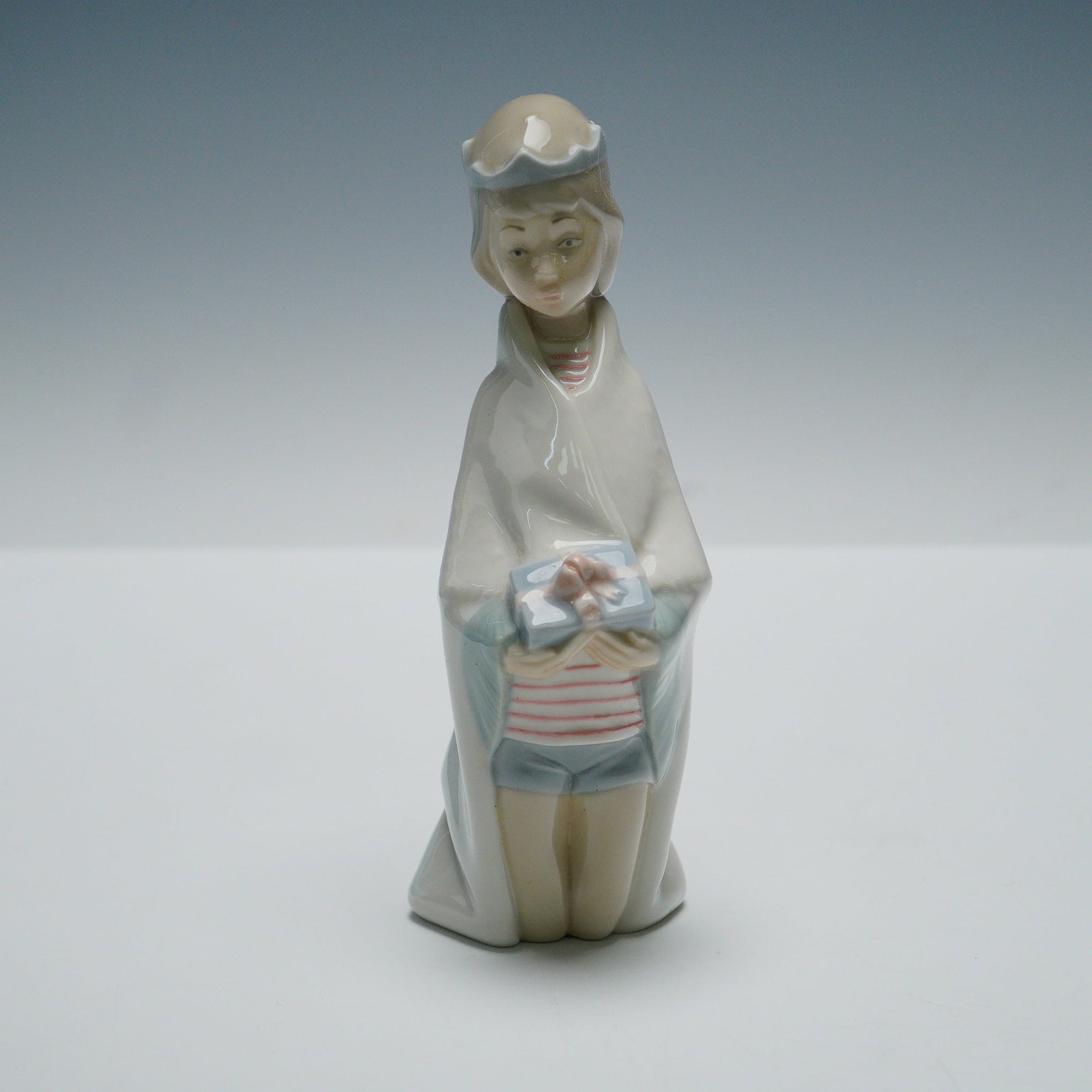 Lladro Porcelain Figurine, King Melchior 1004673: A fine Lladro porcelain figurine titled King Melchior, model number 1004673, depicting one of the Three Kings kneeling while presenting a gift. Finished in soft pastel tones with high glaze, the figur