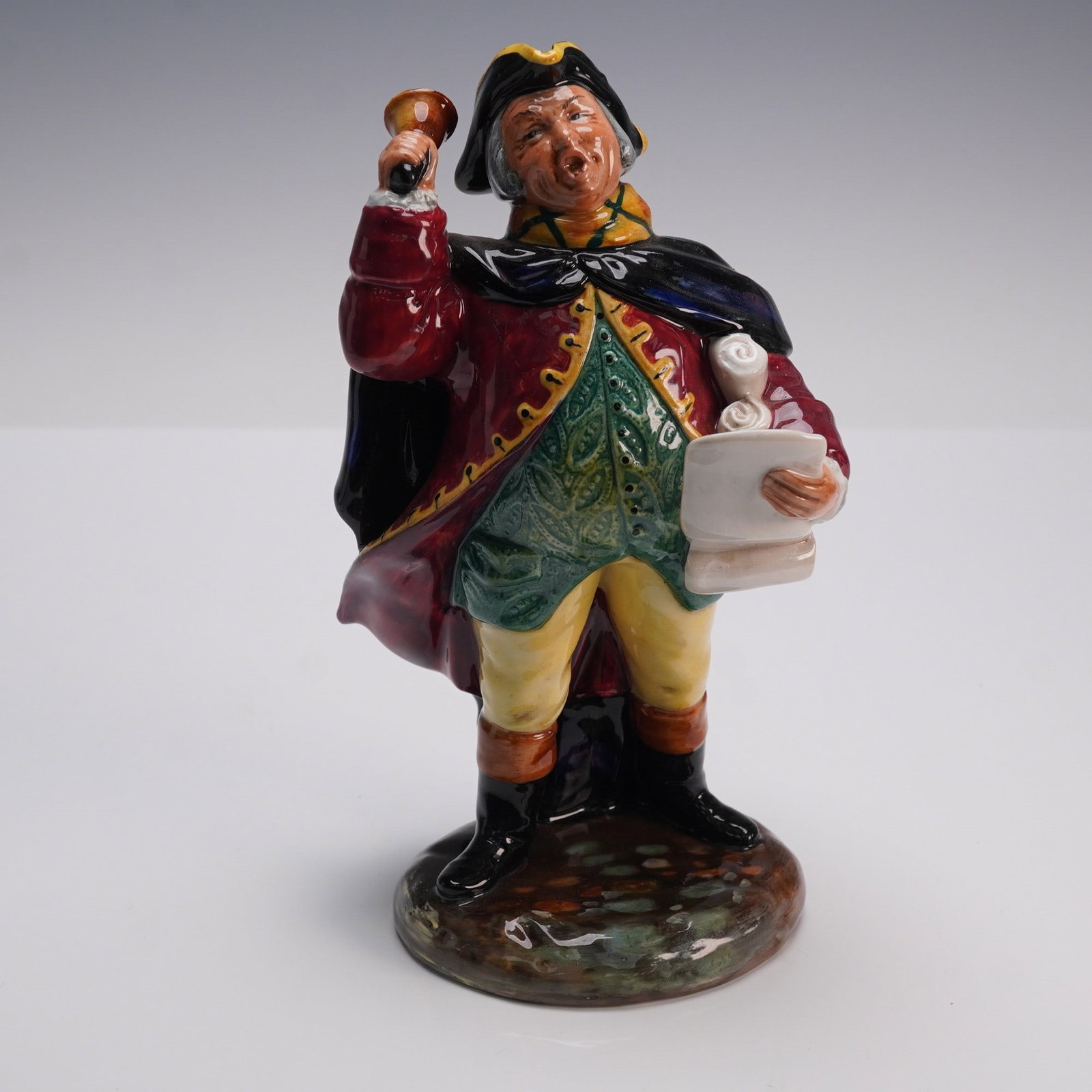Royal Doulton Figurine, Town Crier HN2119: A Royal Doulton porcelain figurine titled Town Crier (HN2119), designed by M. Davies and first issued in 1952. The figure depicts a lively town crier in period attire, standing with one hand raised ho