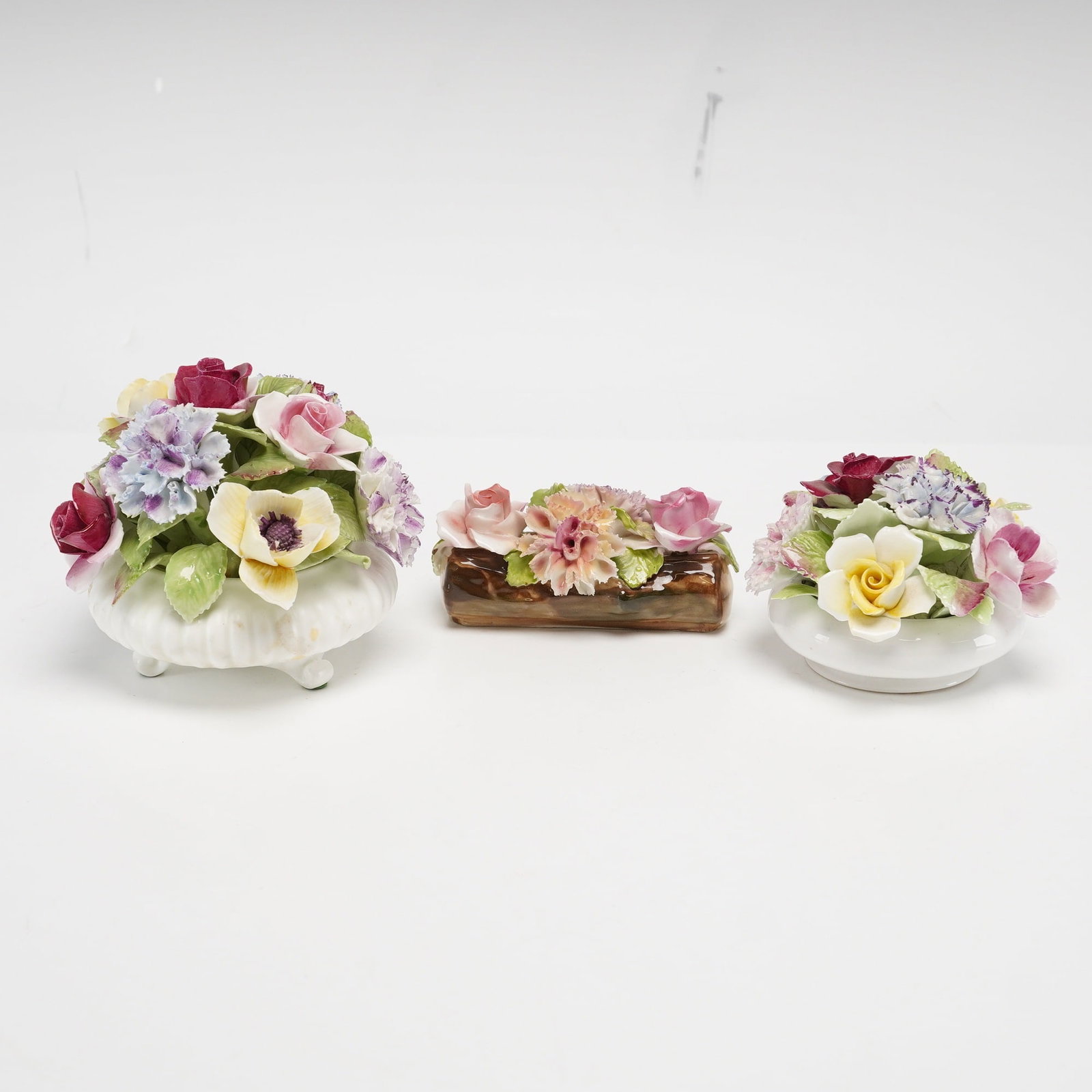 Three English Bone China Flower Display Ornaments Including Royal Doulton and Royal Adderley: This lot consists of three hand-modeled and hand-painted ceramic flower display ornaments. The first item is a Royal Adderley bone china arrangement featuring an assortment of flowers including roses,