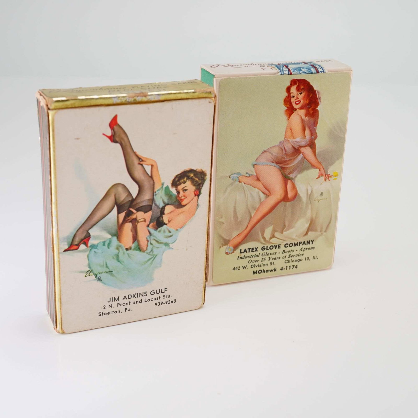 2pc Gil Elvgren Brown & Bigelow Advertising Pin-Up Playing Card Decks: This set of erotica playing card grouping features two vintage decks of advertising playing cards published by Brown and Bigelow under the Remembrance brand. Both decks feature pin-up illustrations by