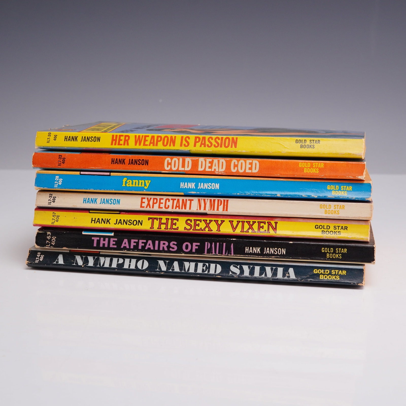 7pc Pulp Fiction Novels. Gold Star Books, circa 1960-1962.: This collection of seven vintage mass-market paperbacks features a sequential run of titles by author Hank Janson, all published by Gold Star Books in the early 1960s. The set includes Her Weapon is P