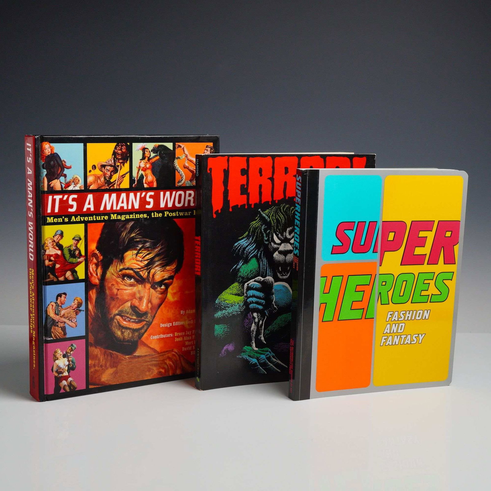 Three Parfrey, Haining, and Bolton Soft and Hardcover Books, It's a Man's World; Terror!; and: This lot comprises three quarto-sized hardcover volumes exploring pulp media, horror illustration, and the intersection of superheroes with high fashion. The first volume, It's a Man's World: Men's