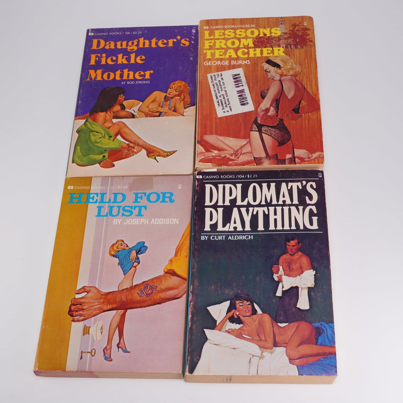 Four Piece Group of Casino 1977 Soft Cover Erotic Fiction: Adult themed books include Lessons from Teacher by George Burns; Daughter's Fickle Mother by Rod Strong; Held for Lust by Joseph Addison and Diplomat's Plaything by Curt Aldrich. Books are used but in