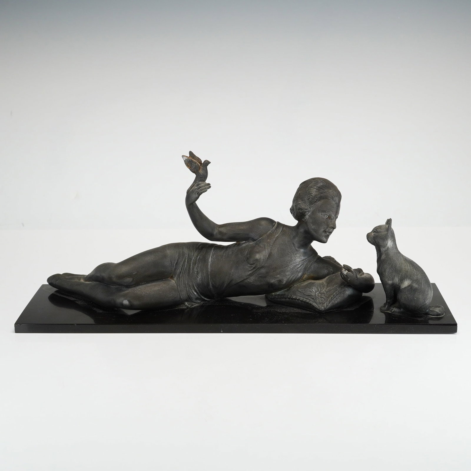 Joan Salvado (Spanish 1890-1976) Art Deco Sculpture, The Favorite, Signed: This Art Deco sculpture by Spanish artist Joan Salvado titled The Favorite (La Femme au Chat et l'Oiseau), depicts a reclining nude female gazing at a seated cat, while her raised hand holds a small b