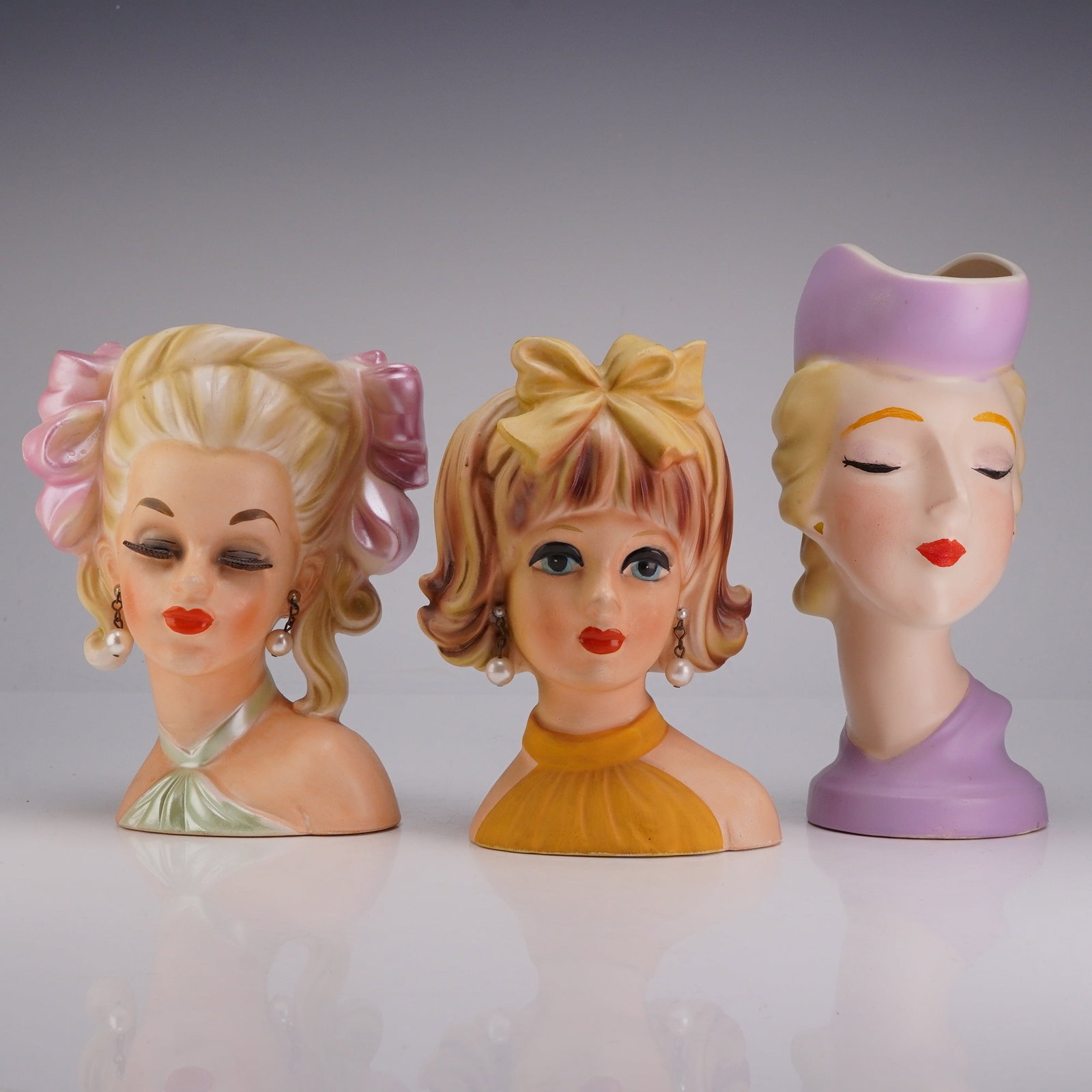 Trio of Mid-Century Japanese Ceramic Lady Head Vases: This trio of mid-century ceramic lady head vases was manufactured in Japan for the export market, likely during the 1950s or 1960s. These styles are frequently associated with American distributors su
