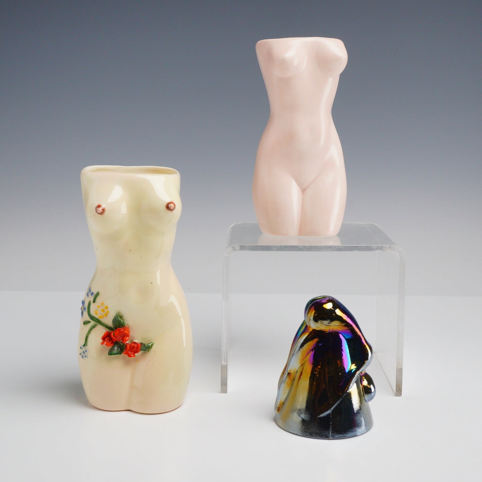 3pc Collection of Female Nude Vases and Cup: This 3pc collection of female nude vases and upside down cups consists of two ceramic vessels and one glass object. The first ceramic vase is modeled as a female torso with an off-white glaze, featuri