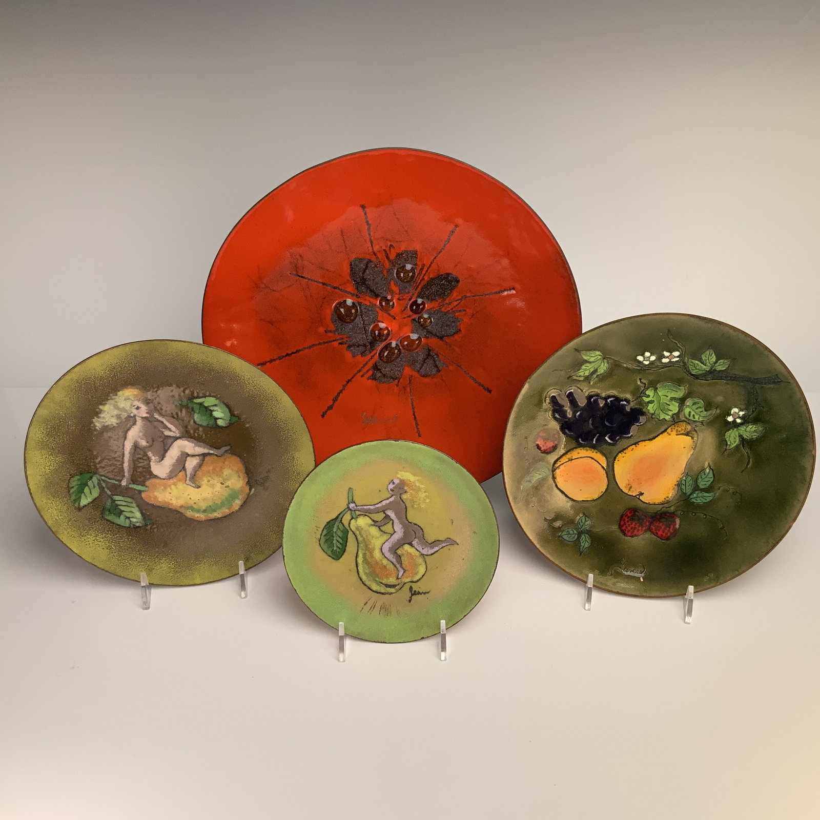 4pc Enamel on Copper Decorative Plates: This collection consists of four decorative plates and chargers featuring vitreous enamel on copper. The assortment includes a large charger with a high-gloss red field, a central black abstract burst