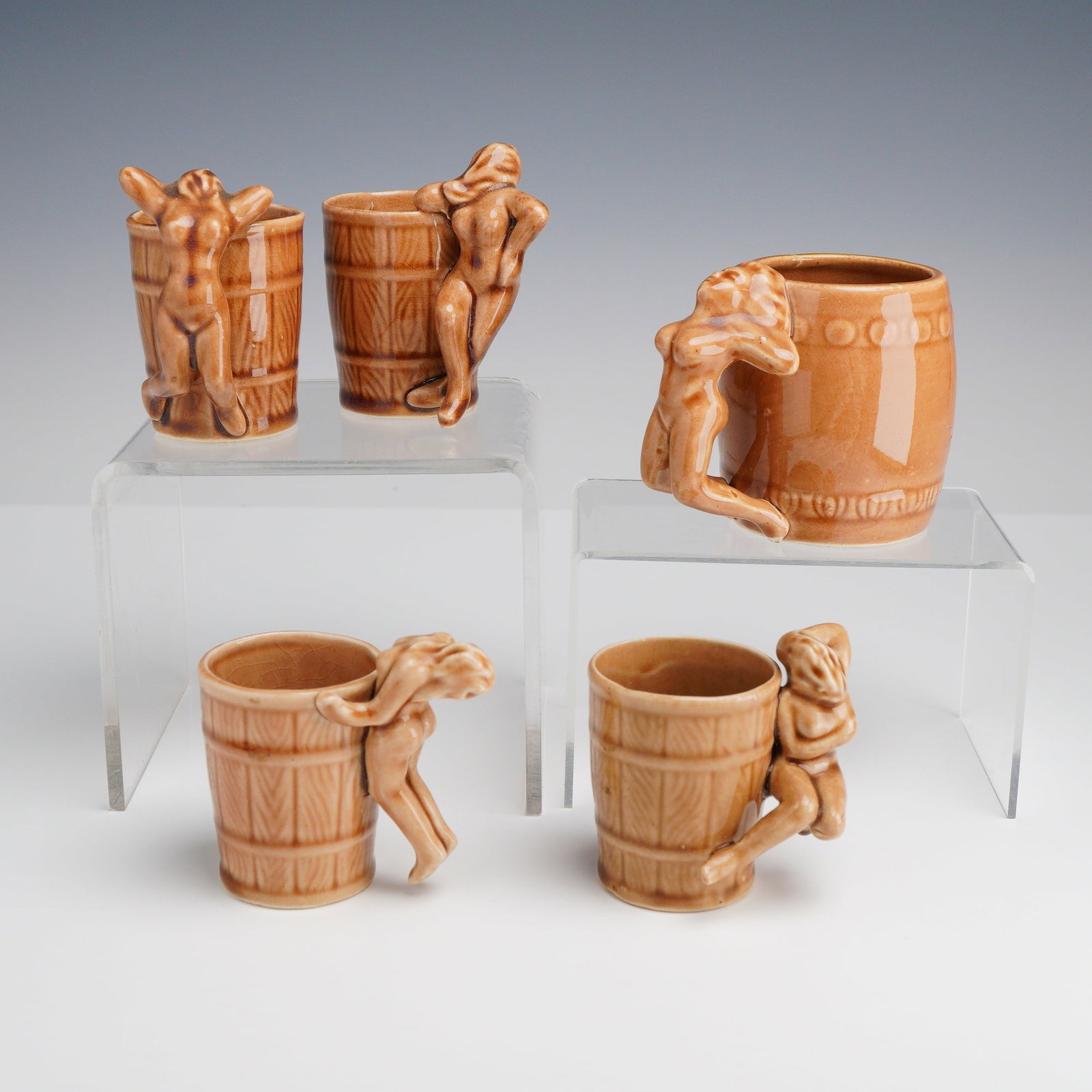 Five Risque Ceramic Shot Glasses and Mug, Attributed to Japan: This set of 5 risque ceramic shot glasses and mug is crafted from glazed earthenware, likely produced in Japan. Each piece is designed in the form of a barrel; the shot glasses feature molded vertical