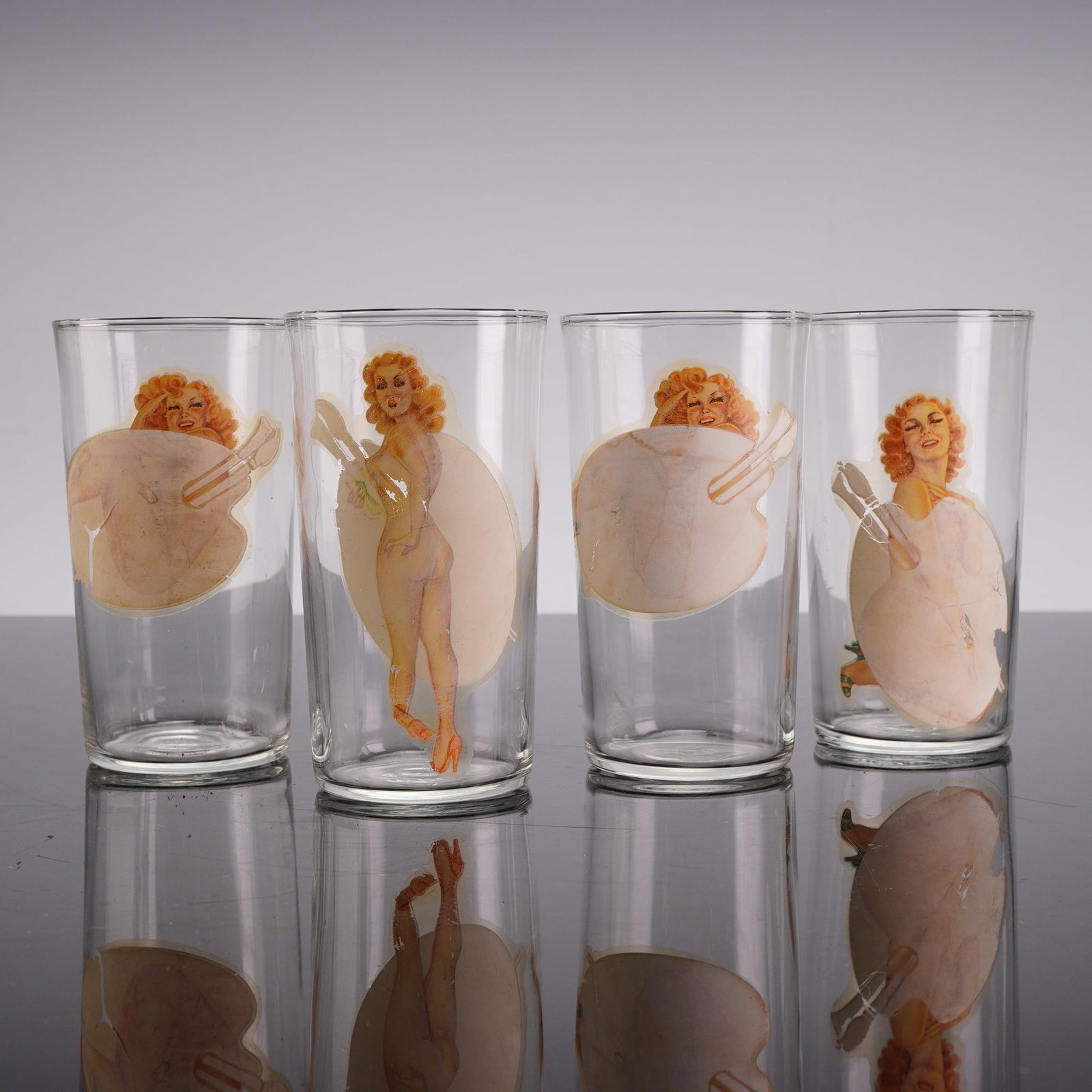 4pc Mid-Century Peek-A-Boo Pin-Up Highball Glasses: A set of 4 risque glasses featuring mid-century American pin-up girl illustrations. These highball-style drinking glasses are constructed of clear machine-made glass with applied multi-color decals. E