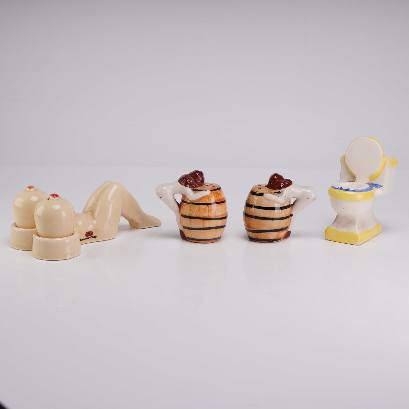 4pc Japanese & American Ceramic Novelty Salt and Pepper Shakers: This lot consists of four mid-20th-century novelty ceramic salt and pepper shakers. The first set is an Atlantic City souvenir comprising a three-piece assembly: a base modeled as a reclining female l