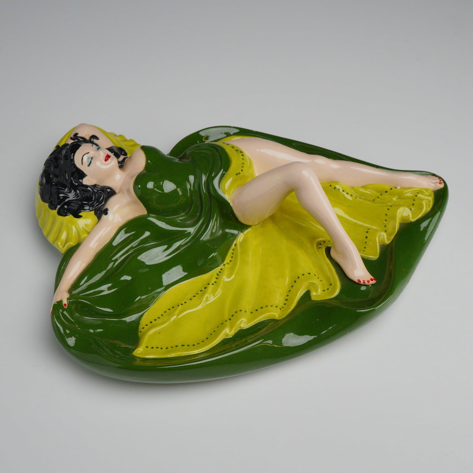 Mid-Century Ceramic Pin-up Style Girl in Green and Chartreuse Ashtray: The piece is attributed to the ceramicist Geza Salyi and bears the incised signature G. Salyi on the unglazed base. The form consists of a shallow, irregularly shaped dish with a three-dimensional pin