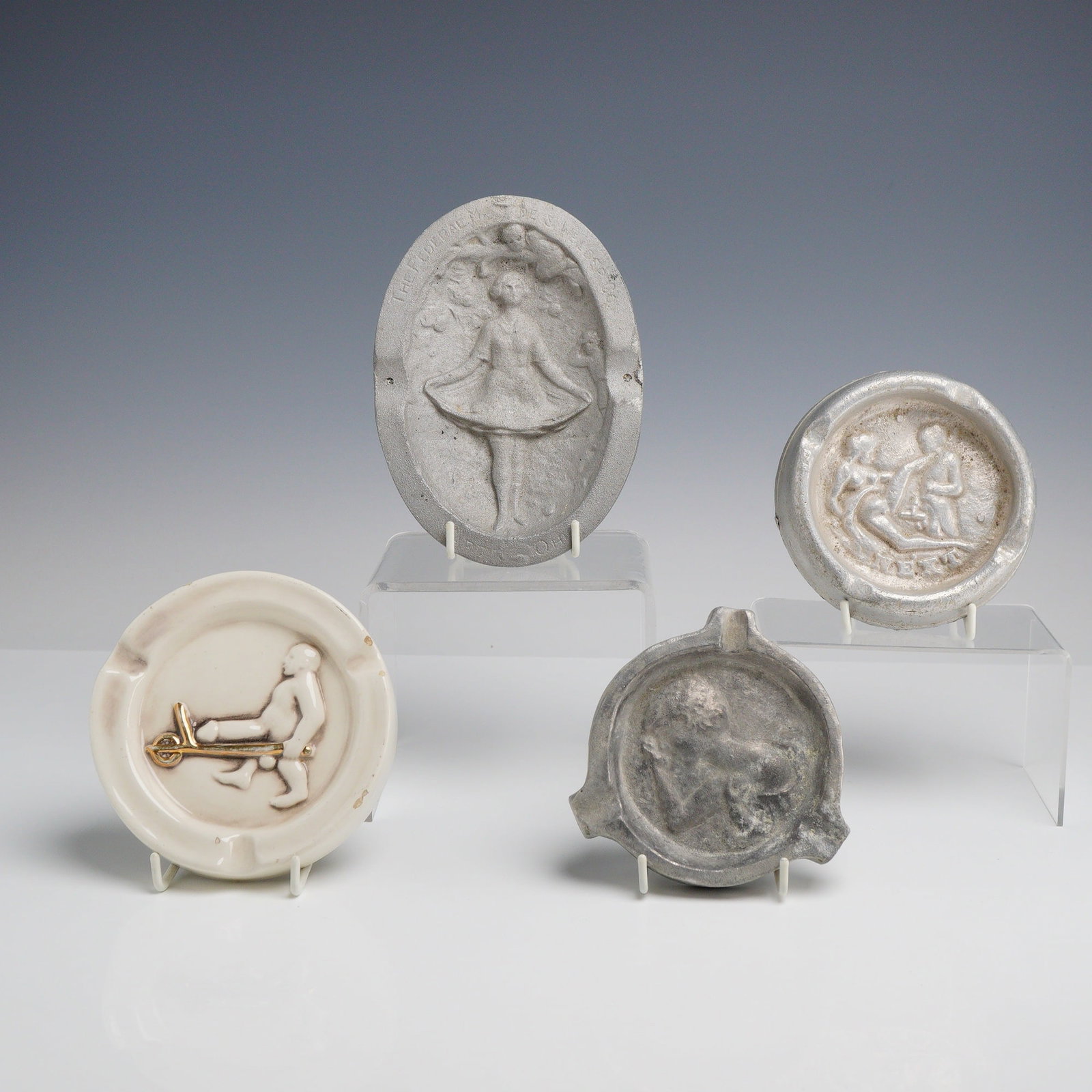 Assortment of Four Vintage Metal and Porcelain Risque Ashtrays: An assortment of vintage metal risque ashtrays and novelty barware, including promotional and speakeasy-style examples of mid-20th-century American origin. The collection features a cast aluminum oval