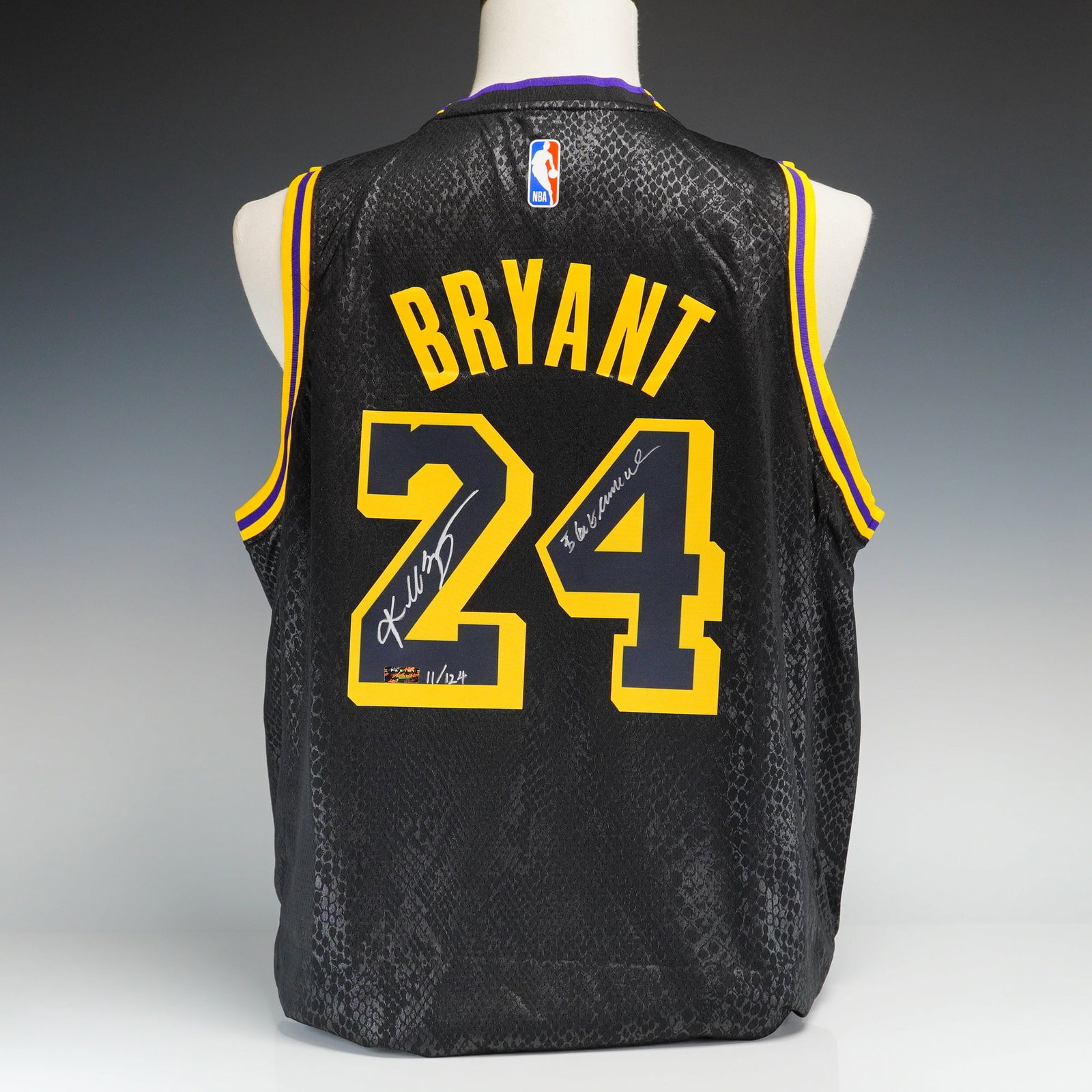 Kobe Bryant Autographed Nike Los Angeles Lakers Black Mamba City Edition Swingman Jersey Limited: A Kobe Bryant autographed Nike City Edition Black Mamba Los Angeles Lakers swingman jersey. The jersey features a black body with a tonal snakeskin-patterned texture, accented by yellow and purple