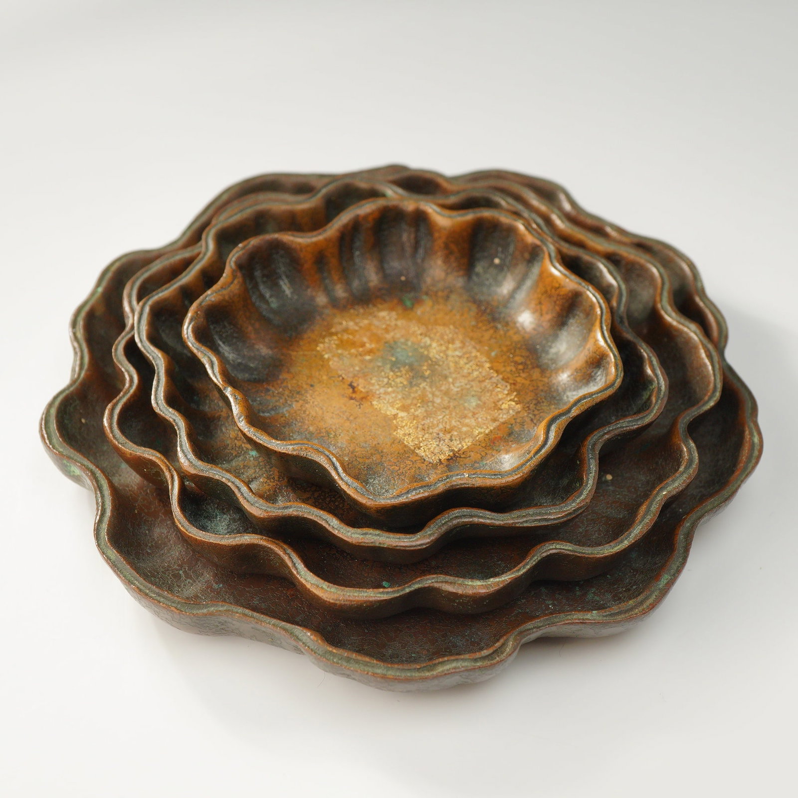 4pc Tiffany Studios Bronze Nesting Nut Bowls: This set of four graduated nesting dishes is produced by Tiffany Studios, New York. Each bowl is cast in bronze and features a multi-lobed scalloped rim in a flower or shell form. The surfaces