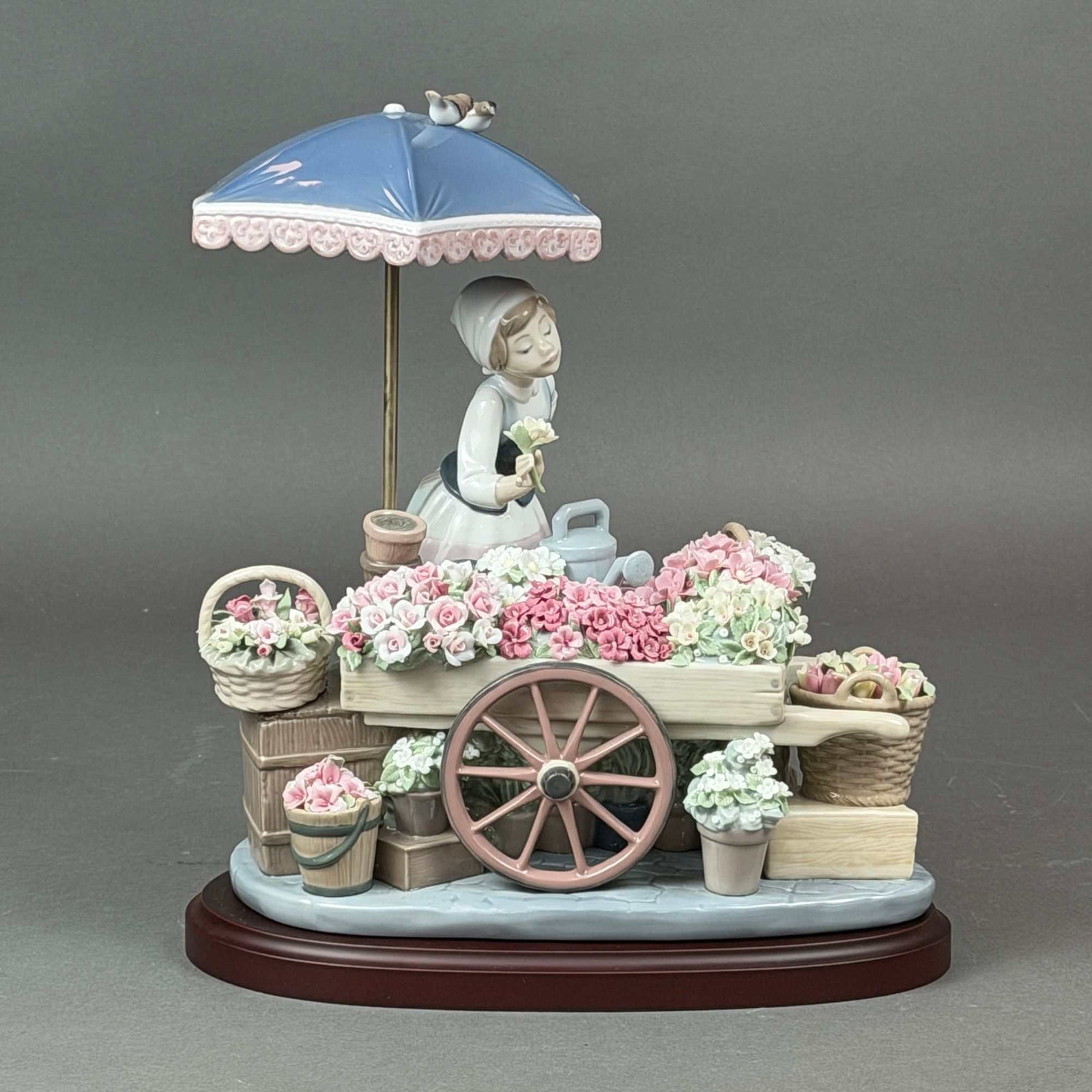 Lladro Figurine with Wood Base, Flowers of the Season 1454: Lladro porcelain figurine titled Flowers of the Season, model number 1454, designed by sculptor Jose Puche. The intricate composition features a young woman in traditional attire tending to an elabora
