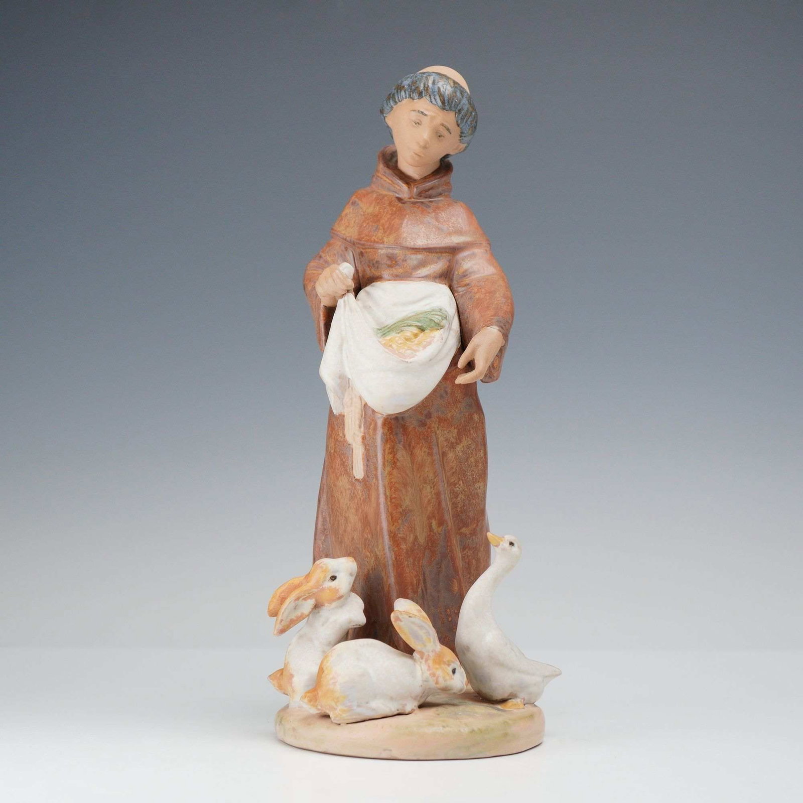 Lladro Gres Porcelain Figurine Farmyard Grace 01012204, Signed: The piece depicts a monk, often identified as Saint Francis of Assisi, dressed in a traditional brown hooded habit with a white knotted cord belt. He is shown standing and holding a white sack of grai