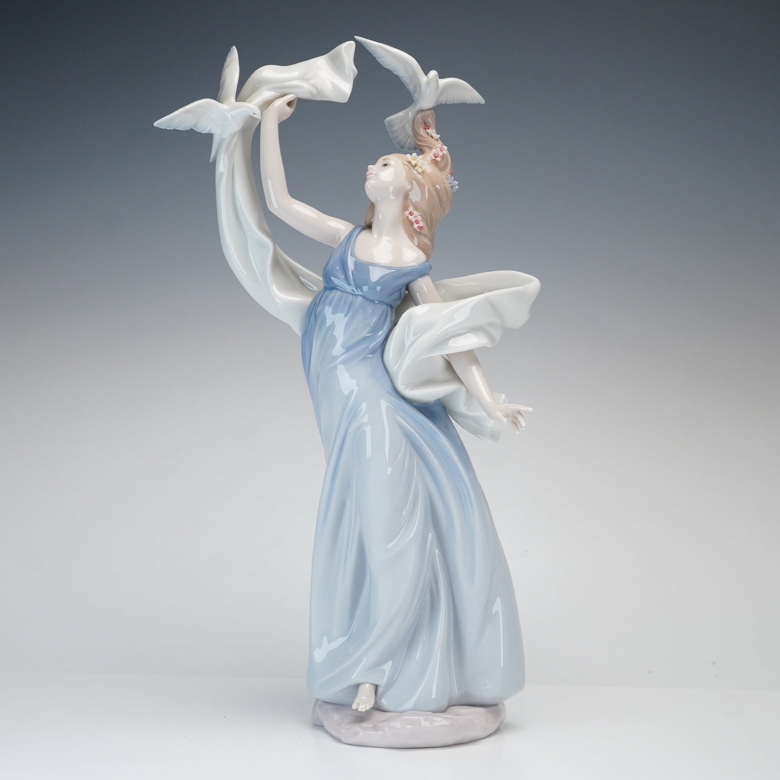 Lladro Inspiration Millennium Porcelain Figurine, New Horizons 01006570: This tall, slender polychrome glazed porcelain figurine, titled New Horizons (01006570), is part of the Lladro Inspiration Millennium collection. The figure depicts a woman in a flowing, pale blue sle