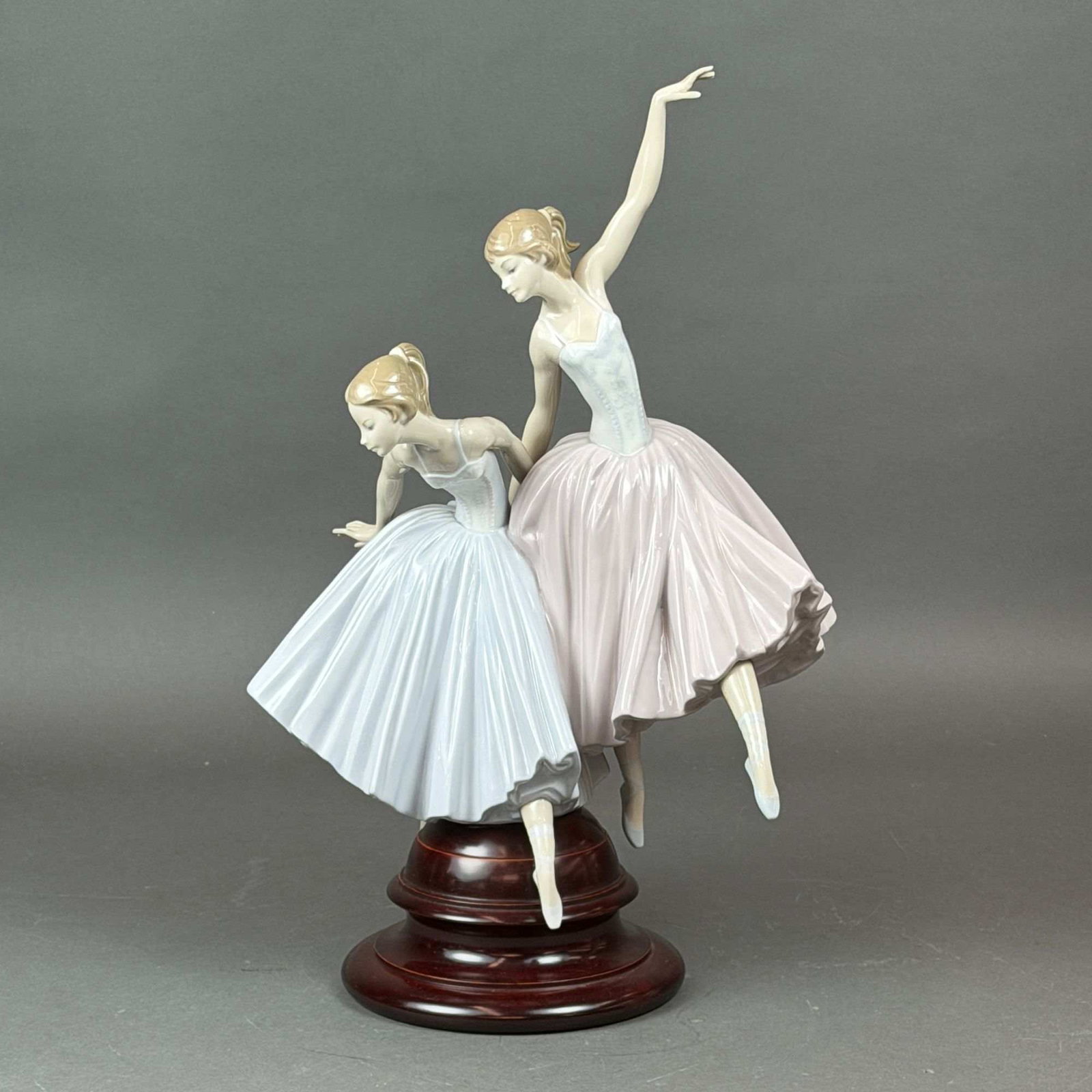 Lladro Porcelain Figurine Act II Number 01005035: Lladro porcelain figurine titled Act II, item number 01005035. This glazed porcelain sculpture depicts two female ballet dancers captured in dynamic, graceful poses. One dancer is dressed in a pale pi