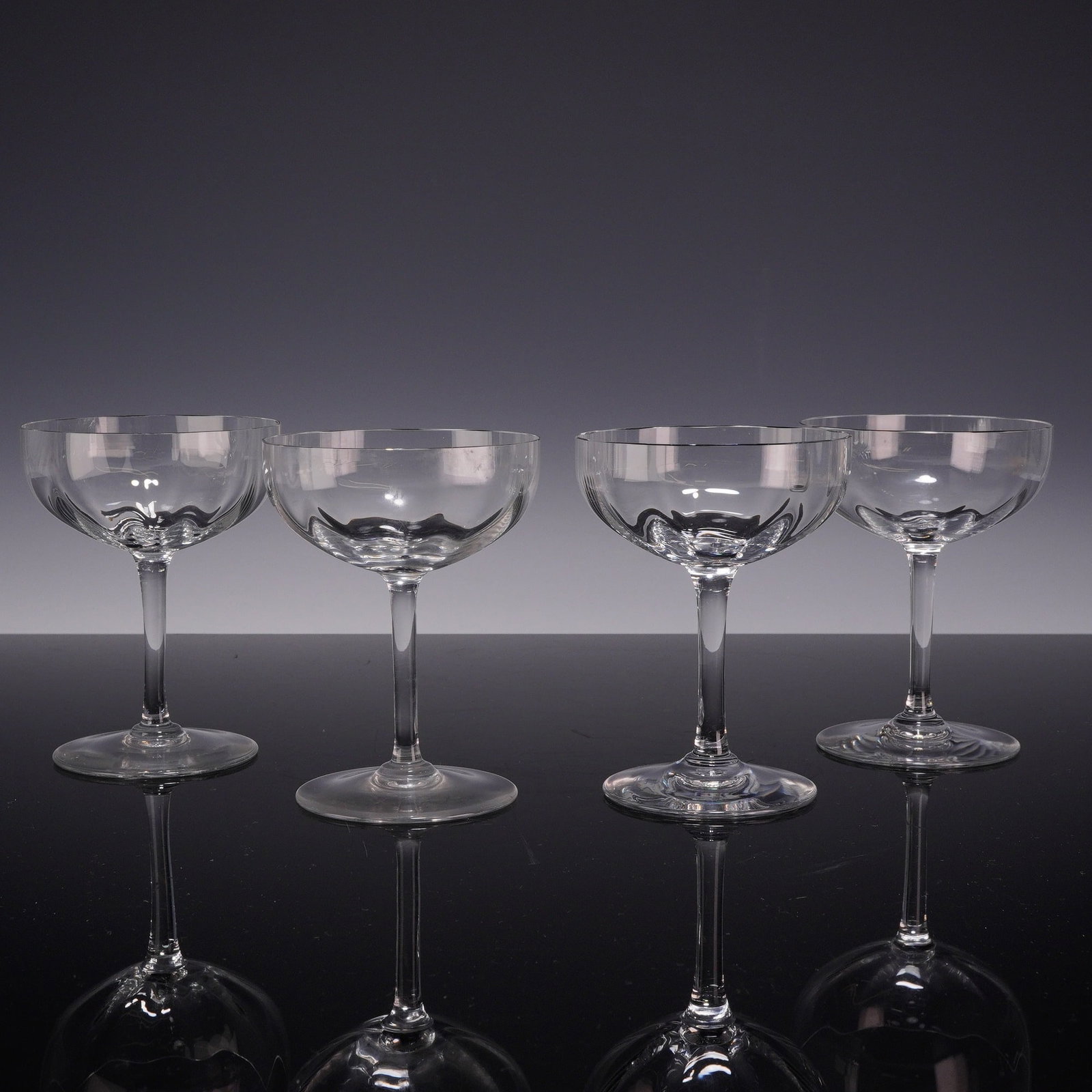 4pc Baccarat Montaigne Optic Crystal Champagne Coupe Glasses: A set of four lead crystal champagne coupes in the Montaigne Optic pattern by Baccarat, France. Each glass features a shallow, wide bowl with an internal vertical optic ribbing that catches the light.