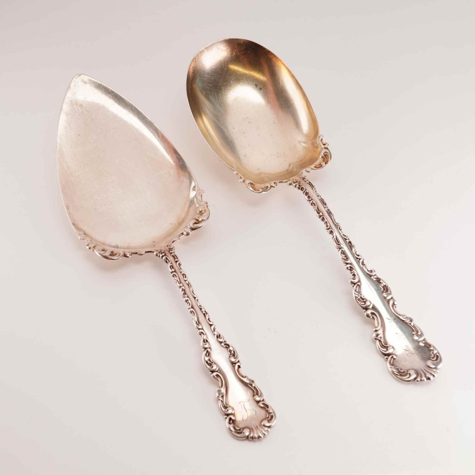 2pc Whiting Manufacturing Company Sterling Silver Serving Pieces: This set of two sterling silver serving pieces is in the Louis XV pattern by Whiting Manufacturing Company. The set includes a flat server with a teardrop-shaped blade and scalloped edges, and a large
