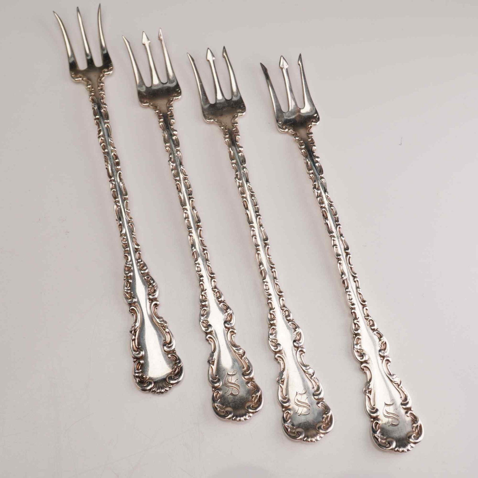 4pc Whiting Manufacturing Company Sterling Silver Oyster Forks, Louis XV: A set of sterling silver oyster forks manufactured by the Whiting Manufacturing Company in the Louis XV pattern, which was patented in 1891. Each fork features a slender, ornate handle decorated in th