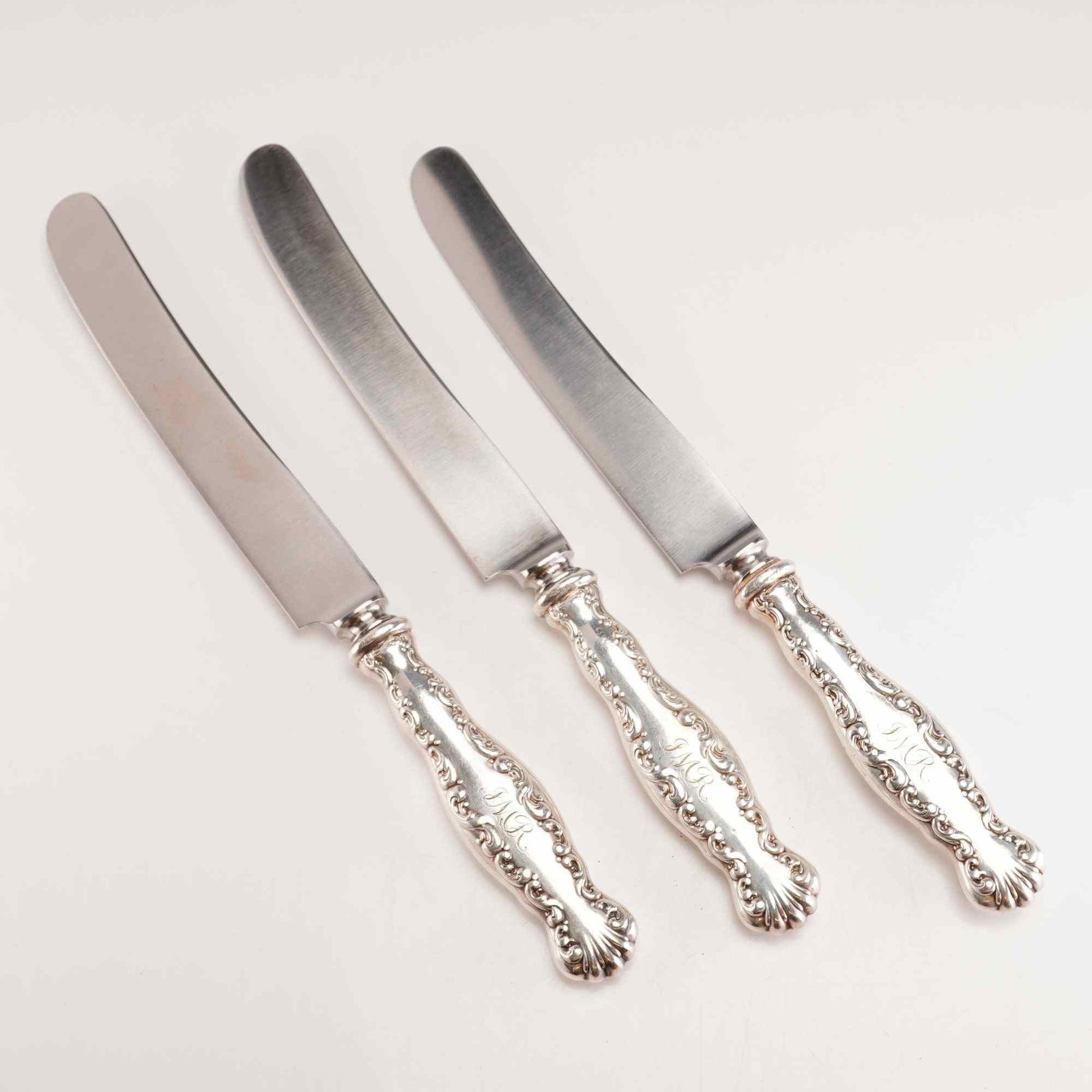 3pc Whiting Sterling Silver Handled Dinner Knives: This set consists of three dinner knives featuring the Lily of the Valley pattern, originally introduced by the Whiting Manufacturing Company in 1885. The handles are constructed of sterling silver wi