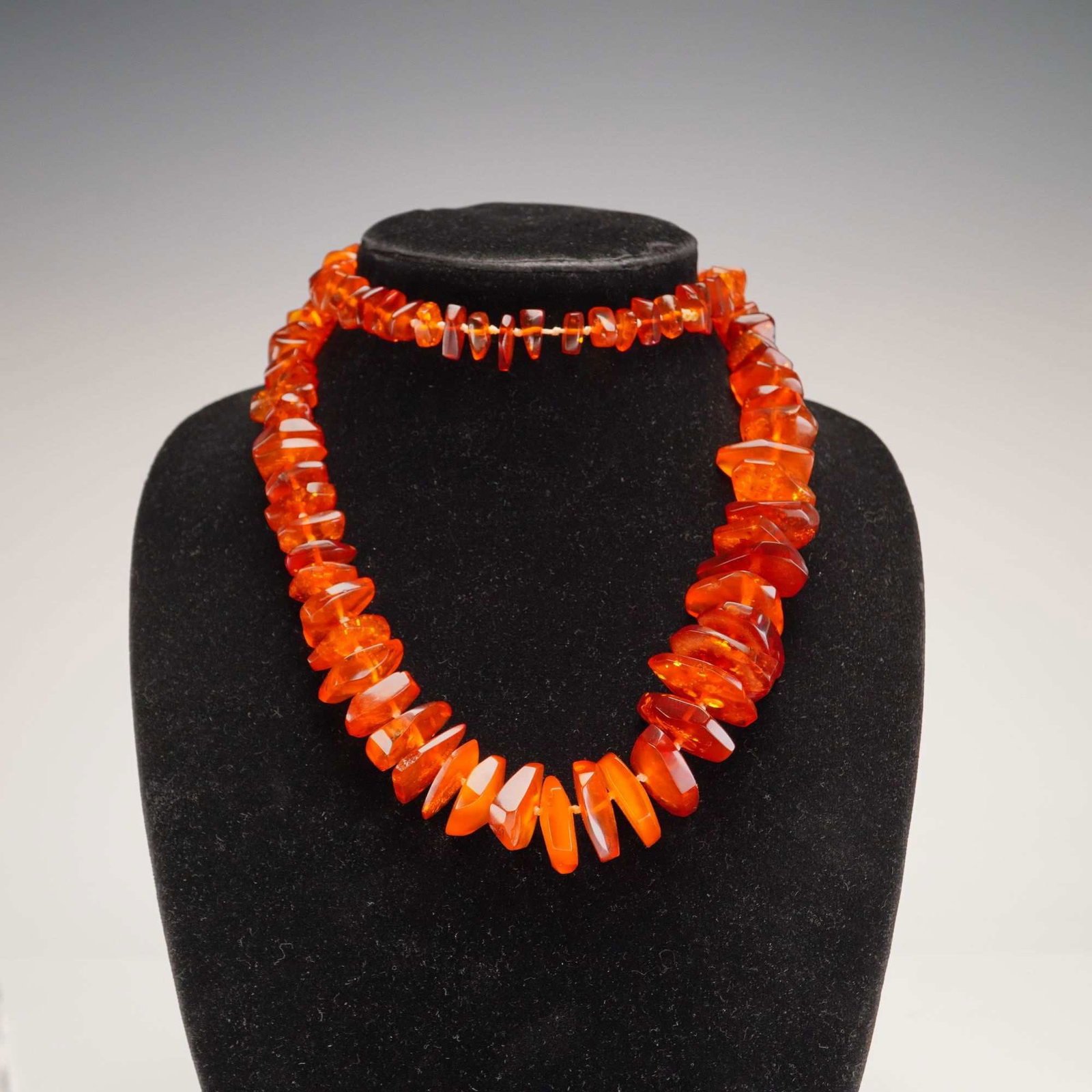 Graduated Amber Nugget Bead Necklace: This necklace is composed of graduated amber beads in a chunky nugget style. The beads display a color palette ranging from warm honey to deep cognac orange. Each bead is translucent and features natu