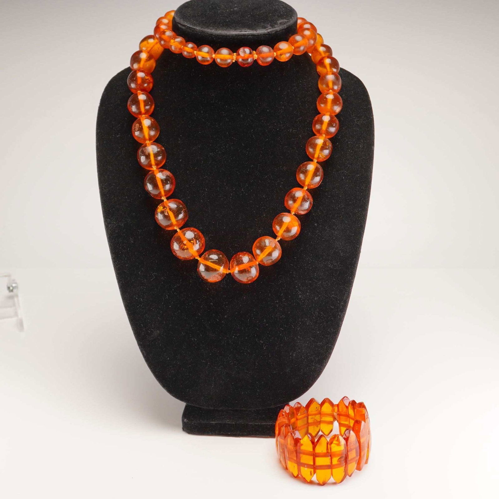 2pc Amber Style Graduated Bead Necklace and Segmented Bracelet Set: This jewelry suite consists of a graduated bead necklace and a faceted segmented bracelet. Both pieces are crafted from a translucent orange-to-honey colored resinous material consistent with amber. T