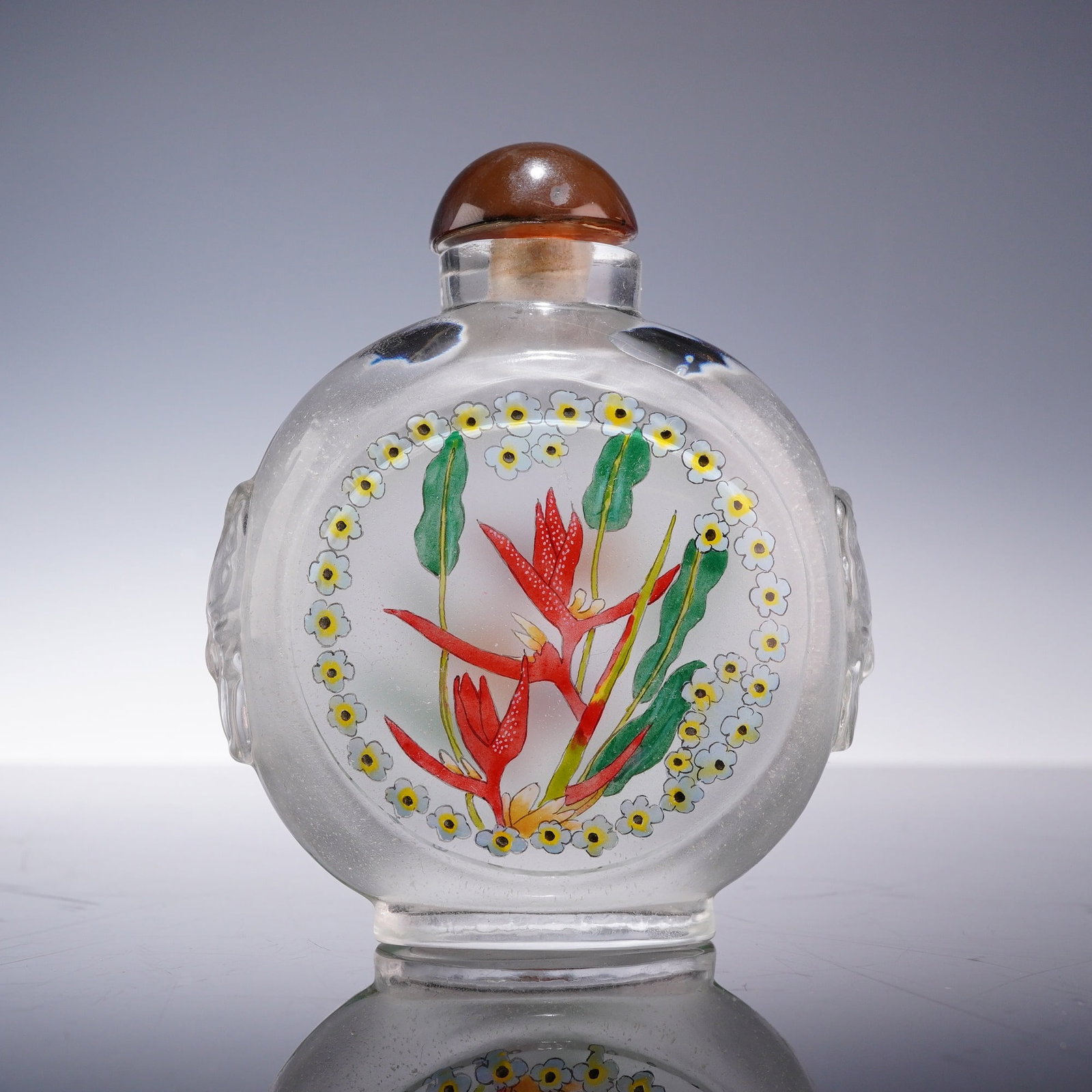 Chinese Reverse-Painted Glass Snuff Bottle with Stopper, Tropical Flowers: A Chinese glass snuff bottle of flattened circular form featuring inside-painted decoration. The vessel is crafted from clear glass with a frosted interior and is designed with a recessed oval foot an