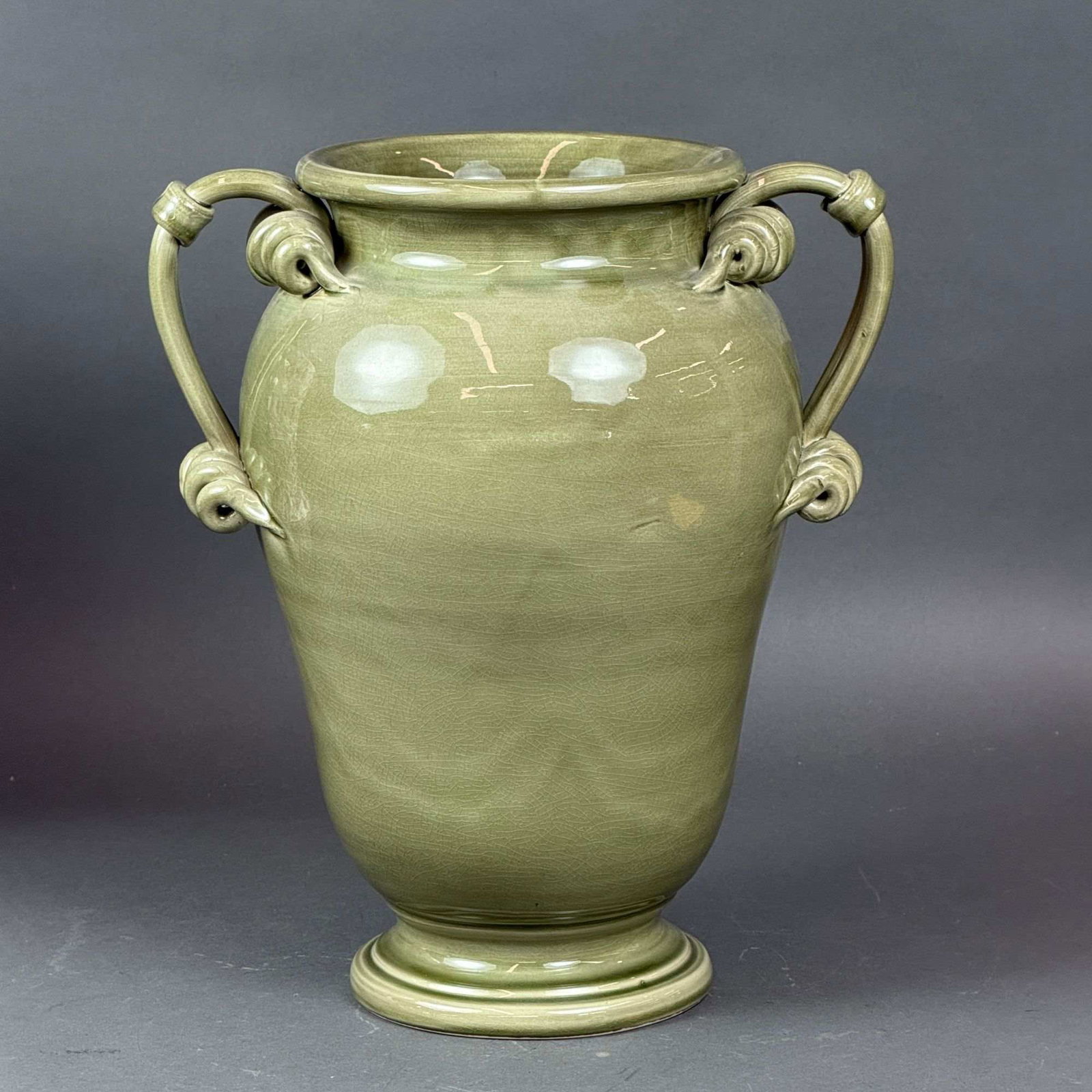 Large Italian Glazed Ceramic Urn Vase: A large-scale Italian glazed ceramic decorative vase of ovoid form. The piece features a wide, flared rim and a tiered pedestal foot. It is designed with two prominent, elaborate handles composed of m