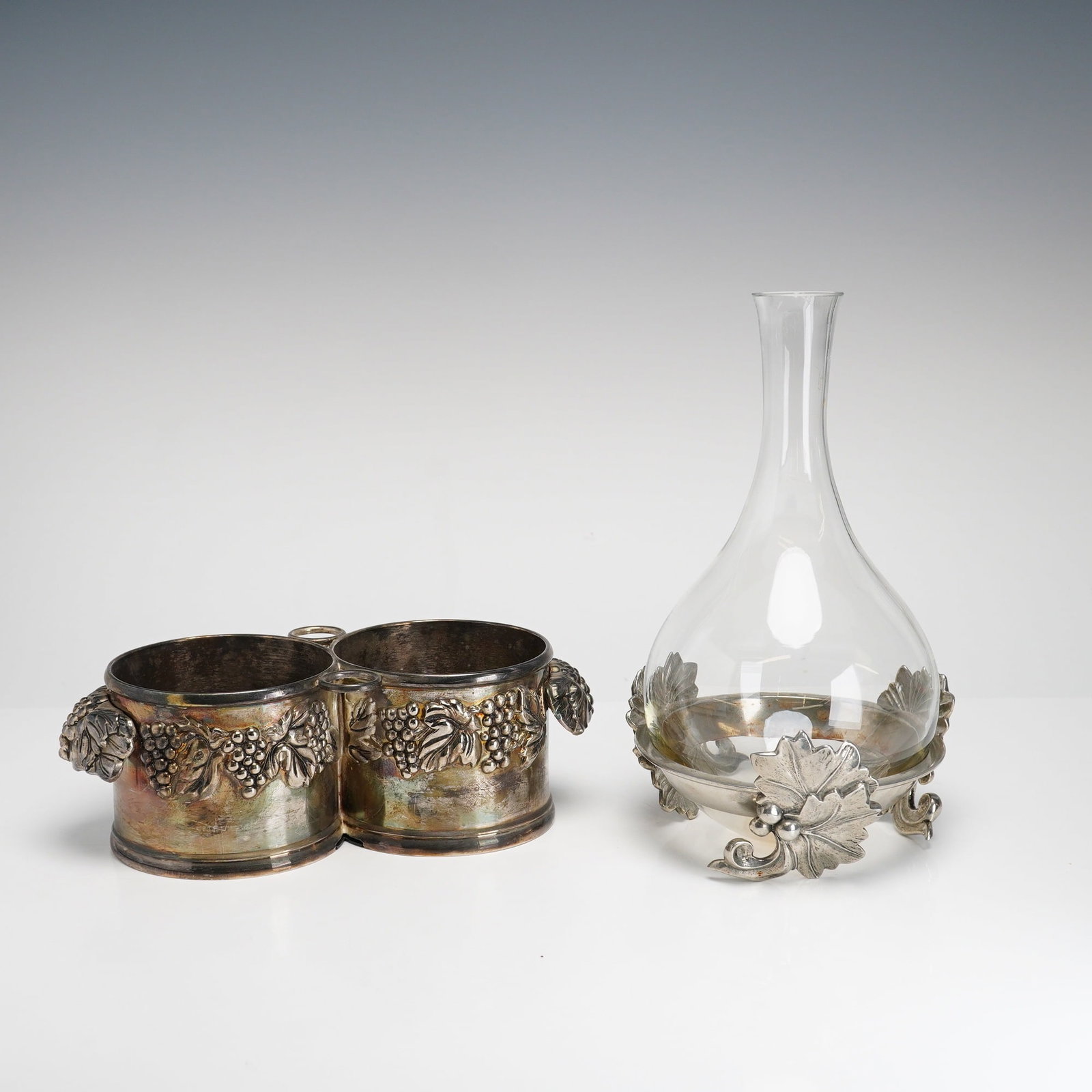 Two Silea Viticultural Wine Service Accessories including a Glass Decanter on Pewter Base and a: This lot features two wine service accessories by the French manufacturer Silea, both showcasing a consistent viticultural theme. The first item is a two-piece glass decanter set, consisting of a clea
