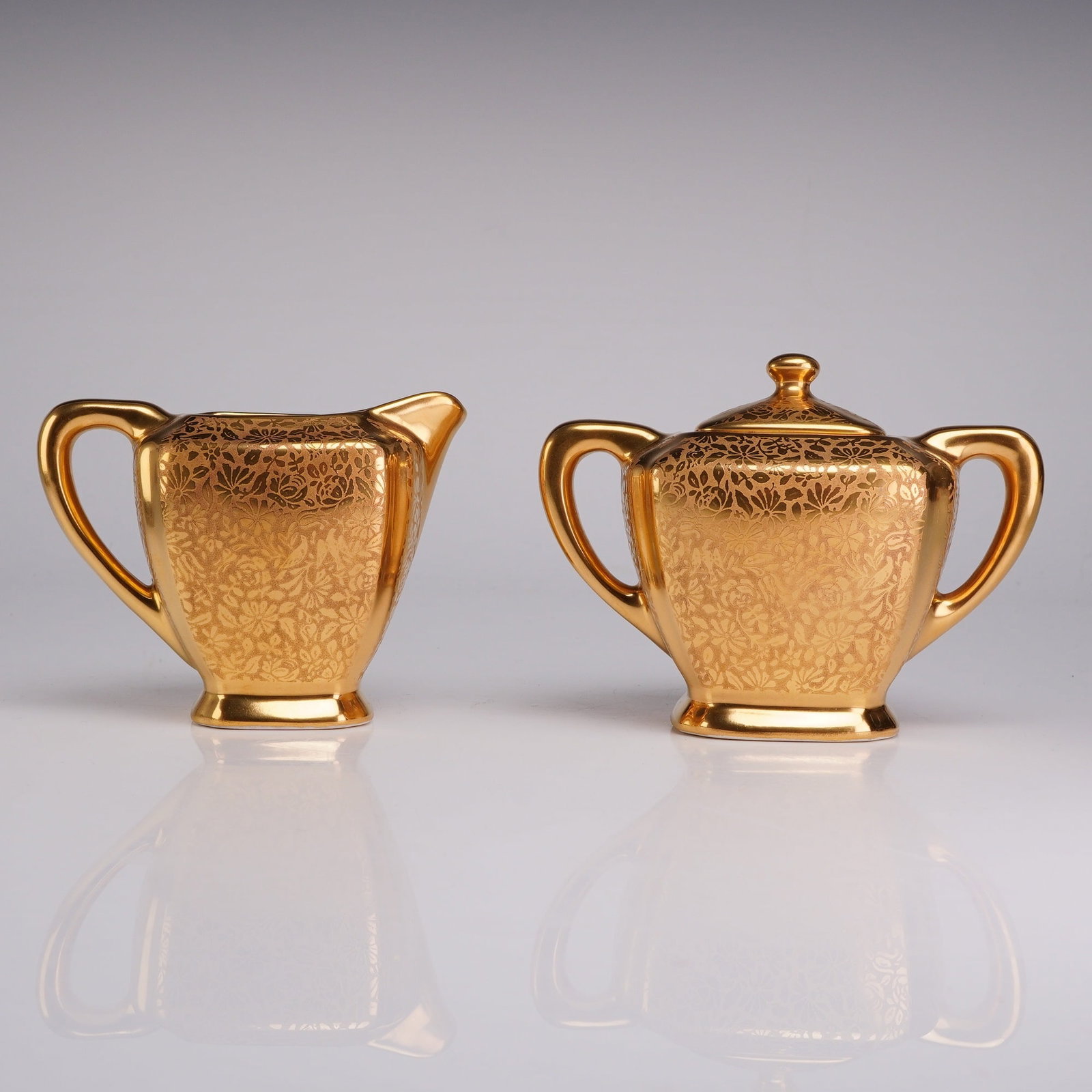 Set of Wheeling Gold China Gilded Covered Sugar Bowl and Creamer Jug: This is a two-piece porcelain set manufactured by the Wheeling Gold China company of Wheeling, West Virginia. The set consists of a creamer jug and a matching covered sugar bowl. Both pieces feature a