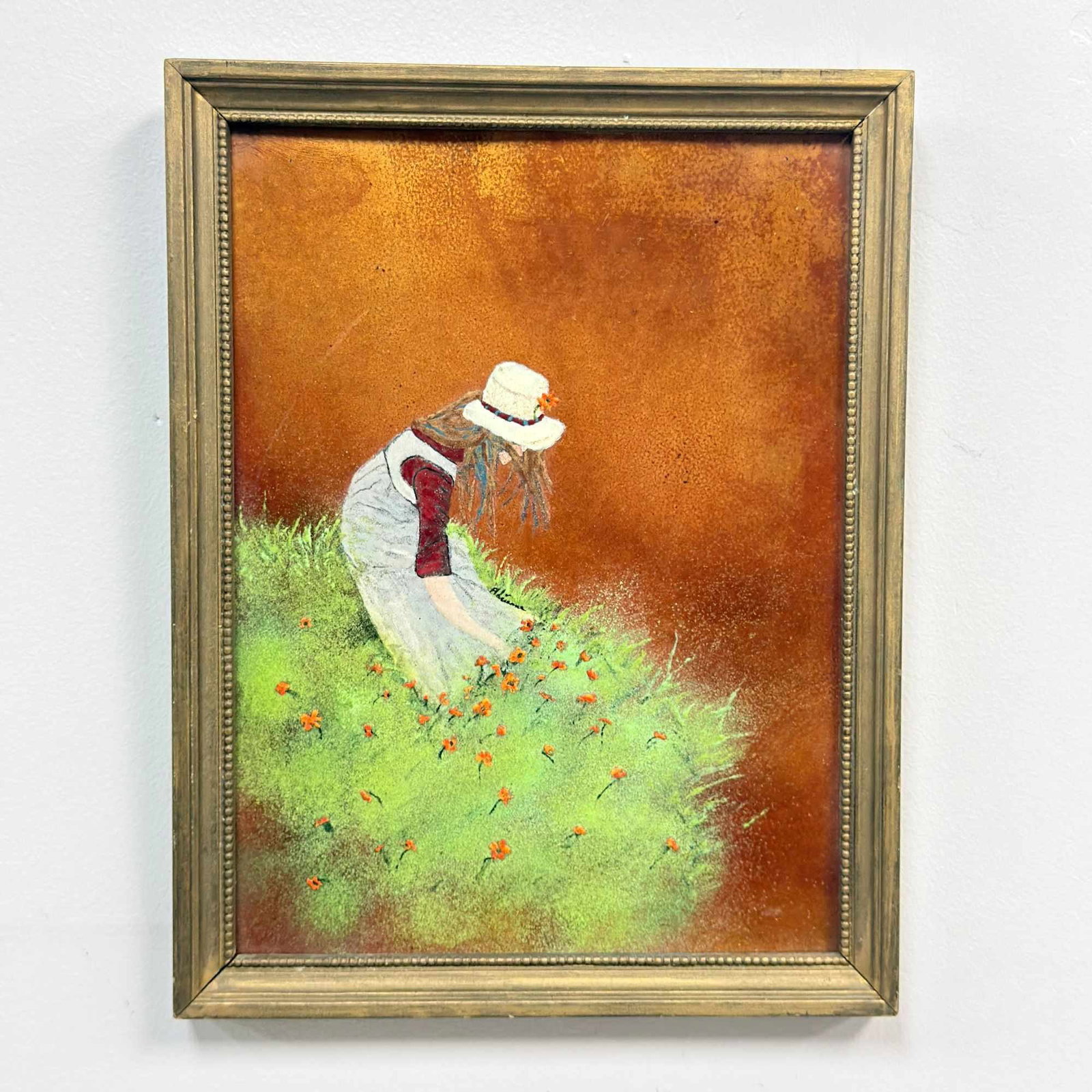 Girl Picking Flowers, Enamel on Copper Painting: This work is an enamel on copper painting depicting a young girl picking orange wildflowers. The figure is shown in profile, wearing a white hat with a decorative band, a white pinafore over a red lon