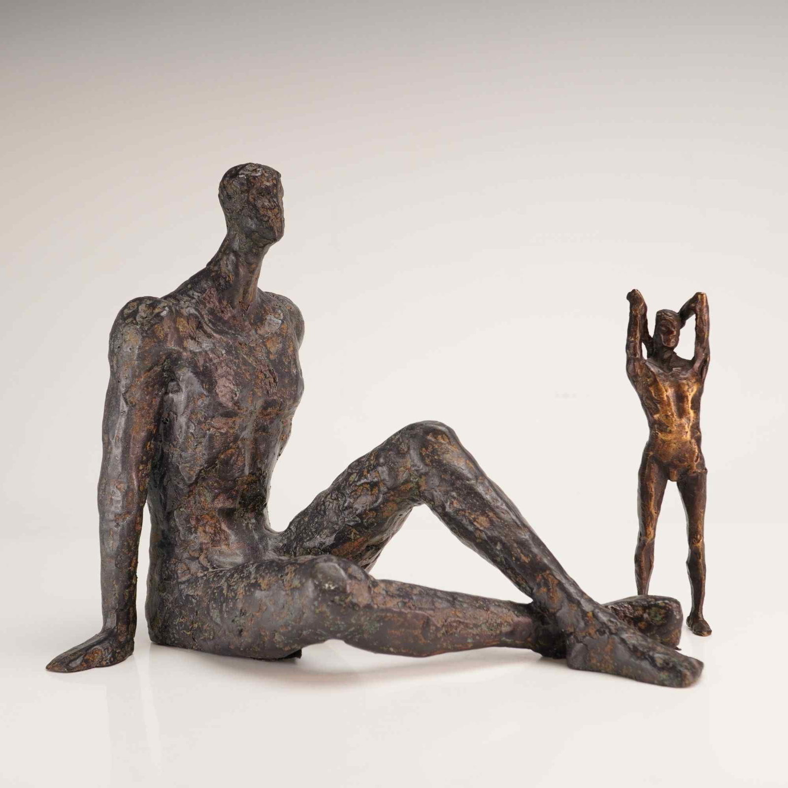 2pc Brutalist Cast Bronze Sculptures, Sitting Man and Standing Man: A group of Brutalist cast bronze sculptures featuring stylized male figures. The first piece is a sitting man with legs crossed and arms braced behind his torso in a reclining pose. The second piece i
