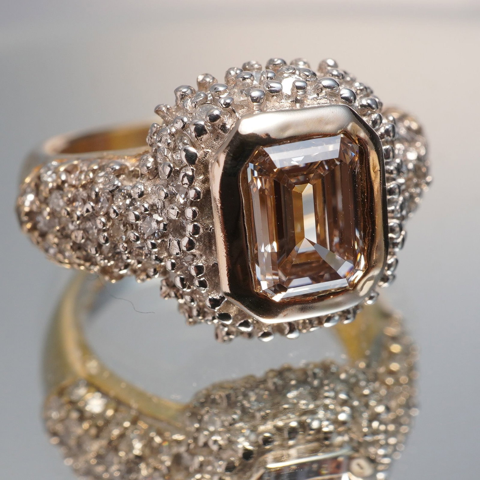 14K Gold Ring with 1.25ct Lab Pink Diamond & 1.52ct Accent Diamonds: Crafted in 14k yellow gold, this striking ring centers on a 1.25 carat emerald-cut lab-created pink diamond, bezel-set in a bold frame. Surrounding it are 84 round brilliant lab-created diamonds