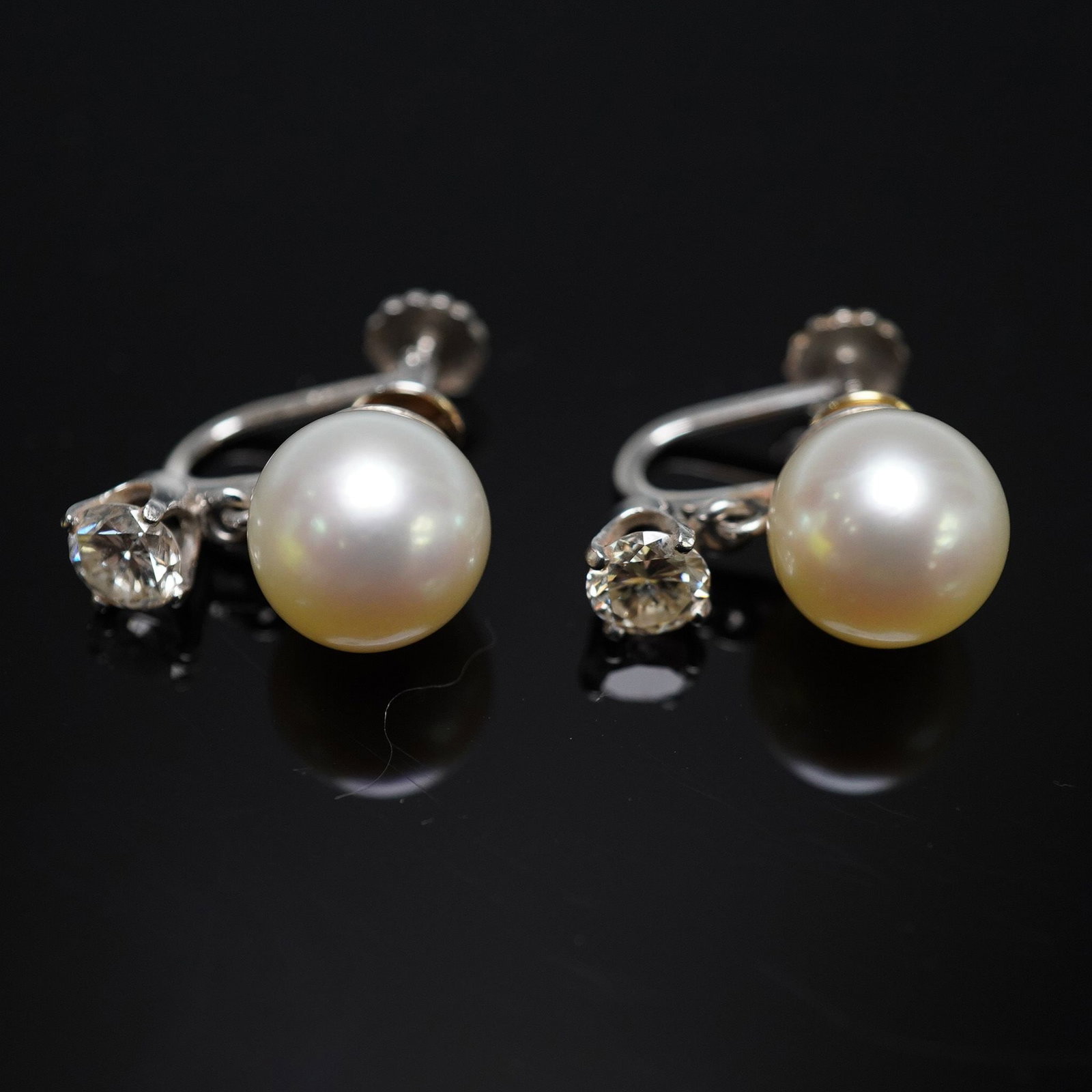 0.70CTW 14K Gold Pearl and Diamond Screwback Earrings: Elegant vintage earrings crafted in 14K white gold, each featuring a luminous cultured pearl suspended below a brilliant round-cut diamond weighing approximately 0.35ct. The diamonds are graded VS1