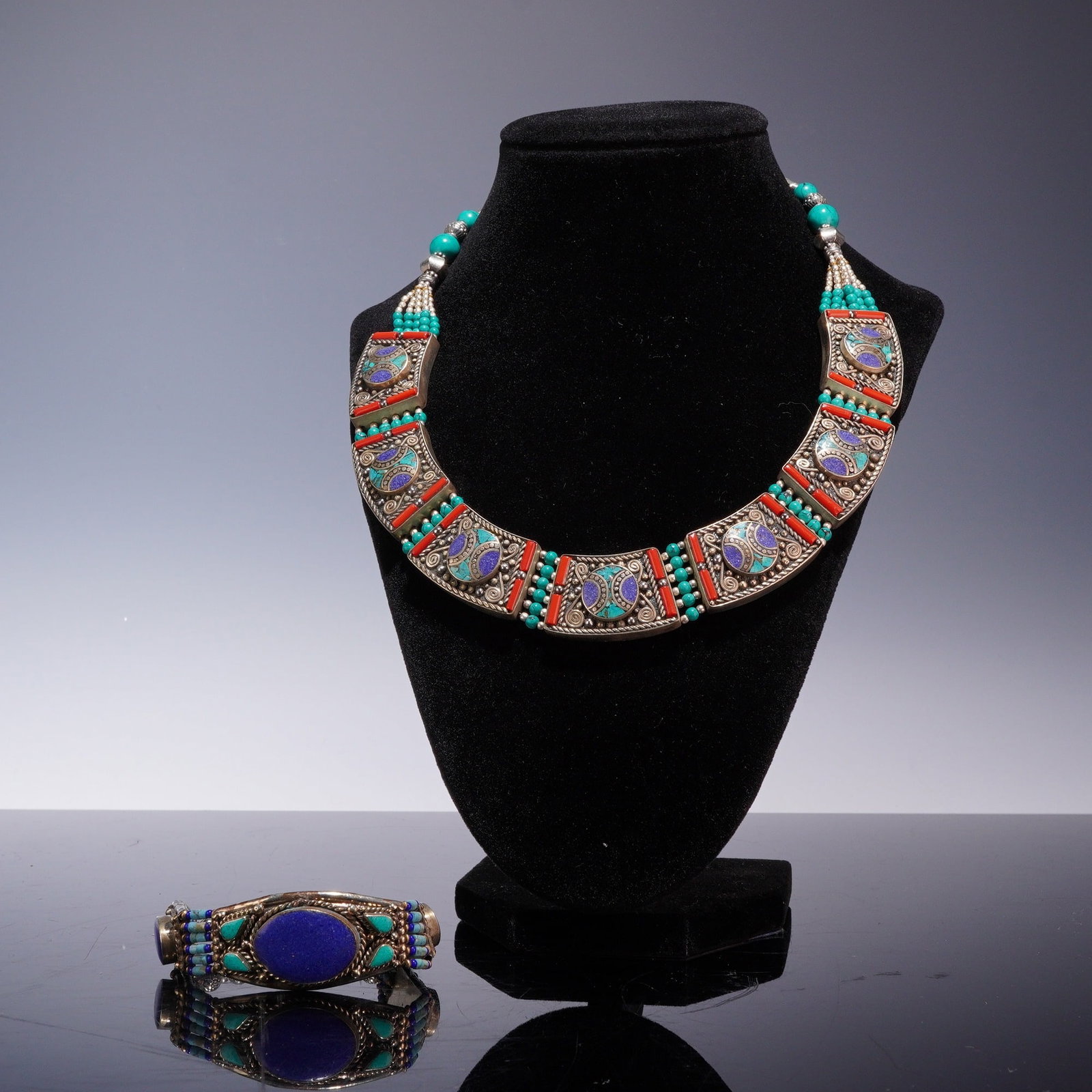 2pc Tibetan Style Turquoise Coral and Lapis Lazuli Costume Jewelry: This two piece jewelry grouping consists of a bib style collar necklace and a matching plaque bracelet. The set is crafted from silver tone metal featuring intricate wirework, filigree, and