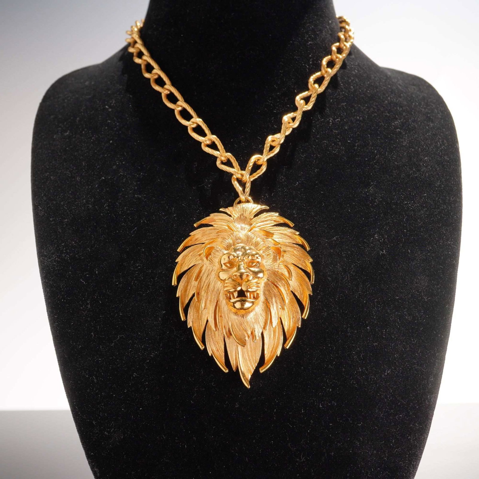 Trifari Gold-Tone Lion Head Pendant Watch Necklace: This vintage pendant watch necklace by Trifari features a substantial gold-tone base metal pendant designed as a stylized lion head with a textured, layered mane. The pendant is hinged at the bottom,