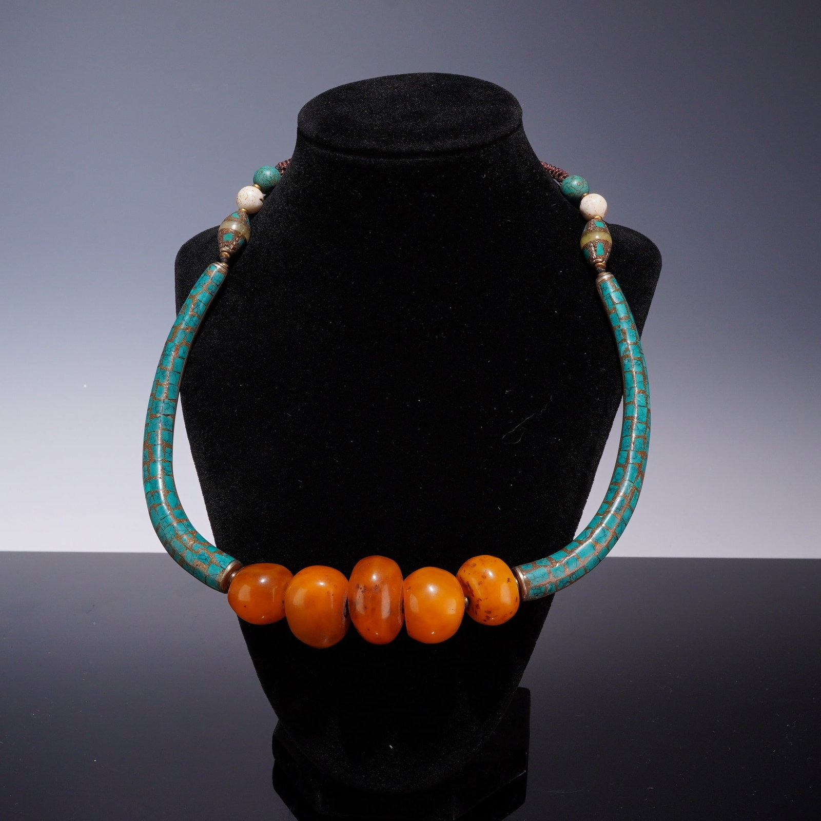 Himalayan Style Costume Jewelry Necklace with Amber and Turquoise Color Accents: This handcrafted collar necklace is designed in a traditional Himalayan folk style, serving as a statement piece of costume jewelry. The design features five graduated, translucent amber-colored