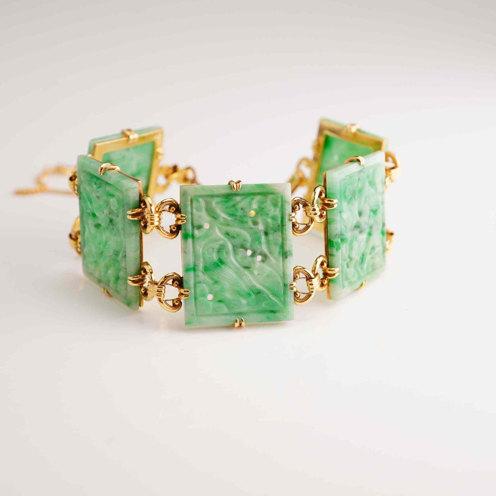 18K Yellow Gold and Carved Jadeite Jade Link Bracelet: This link bracelet is crafted from 18 karat (750) yellow gold and features six rectangular jadeite jade panels. Each panel is intricately carved with foliate and floral motifs and displays a mottled