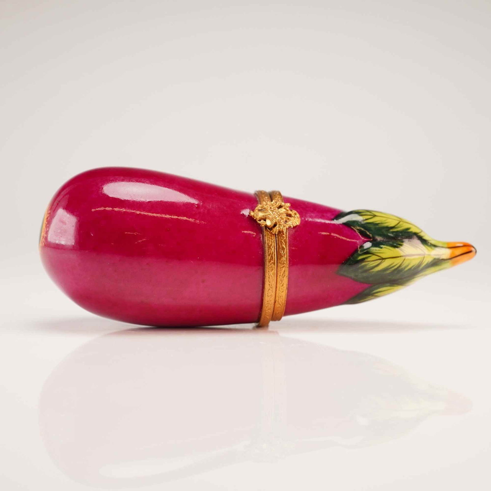 Limoges Hand-Painted Porcelain Eggplant Treasure Box: A French hard-paste porcelain treasure box realistically modeled as an eggplant. The item is finished in a saturated magenta glaze with hand-painted leaves at the stem in shades of green and yellow. T