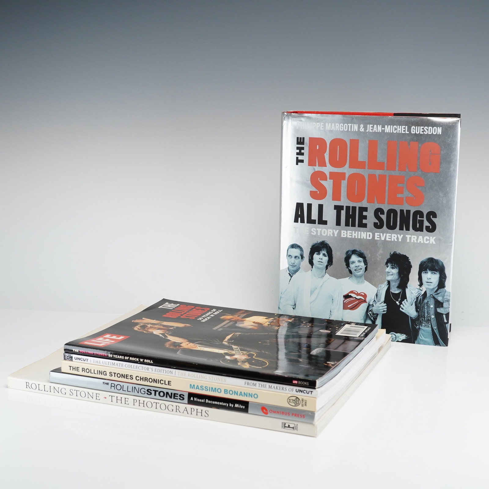6pc Collection of Rolling Stones Hardcover and Softcover Books and Magazines: This 6pc collection comprises a selection of bibliographic works and periodicals chronicling the career of the English rock band, The Rolling Stones. The primary volume is The Rolling Stones All the