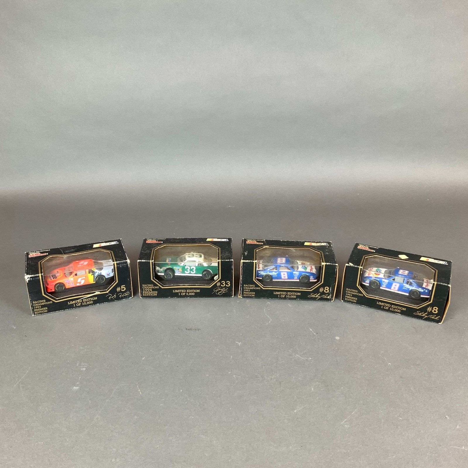 Four Racing Champions Nascar Premier Edition 1:64 Scale Models: A collection of four Racing Champions NASCAR Premier Edition die-cast stock cars in their original display packaging. These 1:64 scale models represent prominent drivers and teams from the 1993 and 19